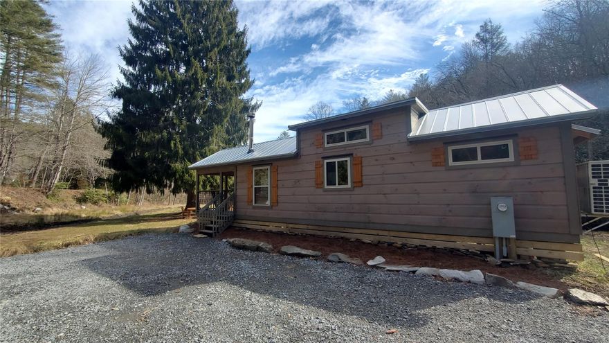 2.4 acres of partially cleared, unrestricted land with a “tiny cabin” and a peaceful stream. Nestled in the ridges on the way to the Blue Ridge Parkway, bordering Pisgah National Forest. Perfect for weekend getaways or as a VRBO.

The 399 sq. foot Tiny House on Wheels was custom built by Sweet Haus in South Carolina in May 2022. It is constructed out of solid logs. A covered porch greets you as you walk into the house with all natural wood counters, walls, cabinetry and Scandinavian-style rafter beams. Home  features a substantial kitchen with butcher-block counters, double sink, regular refrigerator and freezer, small dishwasher, double-burner glass cooktop, and convertible multi-use oven/microwave. The bedroom with a queen-sized bed platform. The bathroom is roomy with a full bath tub and shower. The airy and bright loft is also large enough for any-size mattress or several twin beds.  The house is heated and cooled via two Mitsubishi Electric Mini-splits as well as a wood stove.