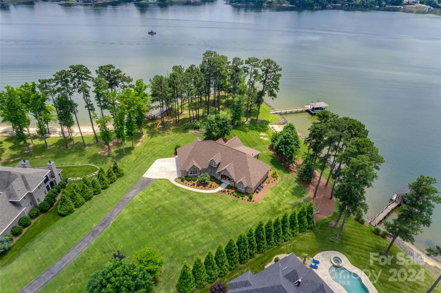 This one has the WOW factor- gorgeously landscaped, flat yard with no steep hill to the dock, sandy beach area & grand open views of Lake Wylie from nearly every room. So many upgrades & special features designed into showstopping custom brick & stone waterfront home that is truly move in ready. This peninsula home has 2 primary bedrooms on the main floor. Kitchen w/ custom wood cabinets, granite and hideaway butler's pantry. Gorgeous hardwoods throughout. Upstairs are two more bedrooms, bath and a huge bonus/rec room. Sandy beach is great for launching paddle boards, kayaks or letting the pets play. Covered dock with composite decking, boat lift, two jet ski docks, shoreline is fully rip rapped, outdoor shower, fully finished three car garage. Relax with a great book on your covered rear patio. Private cul-de-sac lot of over 1.3 acres. Luxury waterfront homes surround. Award winning Clover Schools, No HOA dues & low SC taxes! Tons of walk in attic storage. Don't miss this opportunity!