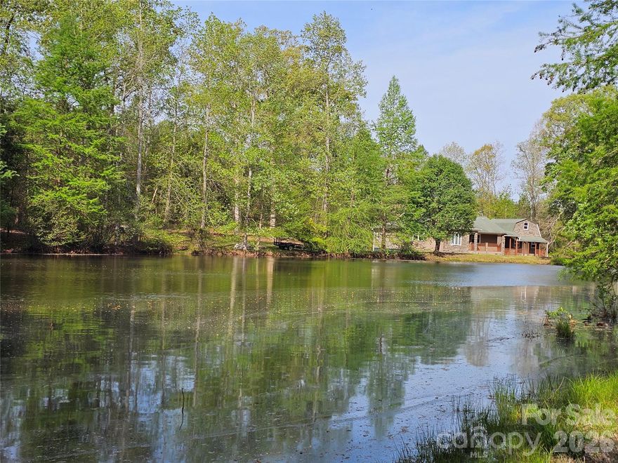 Upon entering the gated entrance of this ±5.396 acre property, you'll witness a beautiful one-acre stocked (catfish, brim & bass) pond.  The secluded gravel driveway continues around the pond changing to asphalt over the dam to the home and various buildings offering country living with options galore!   The ±1494 HSF split floor plan includes 3 bedrooms, 2 bathrooms, and a living/dining area combo with convenient kitchen pass-through.  The sun-lit roomy kitchen includes refrigerator, electric range, built-in microwave, dishwasher and large pantry.  The primary bedroom includes extra bonus area/oversized closet (one gun safe probably remains) and en suite.  Additionally, a laundry room provides a washer and dryer (optional) with access to the rear 384 SF deck.  A detached ±384 HSF home office (previous use) is connected via covered front porch and includes a full bathroom on the main level and interior stairway to an unfinished second floor of approximately the same size. Additionally, the ±1,224 HSF oversized three-bay garage provides RV/camper/boat storage, natural gas heat and central air conditioning with plenty of workshop space.  The wood interior really looks great plus a built-in workshop desk is ready and waiting.  Additionally, a 2-post freestanding automotive lift and upright air compressor are negotiable.  If that wasn’t enough, also included is a detached wired storage building and adjacent dog kennel.  There is also a metal carport, a couple misc sheds and a secluded shipping container.  The backyard is fenced with an additional fenced area for a garden plus more.  All of this located 2 miles from I-77 (Exit 65) and Lewisville Schools!  Get out the fishing rods, lawn chairs and maybe a kayak to really enjoy the pond.