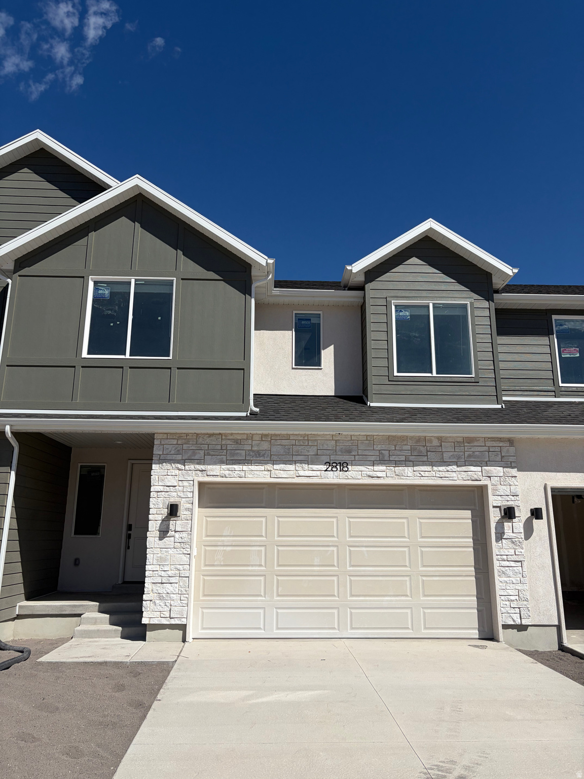 Contemporary facade featuring a two-car garage, stone veneer accents, and multi-pane windows