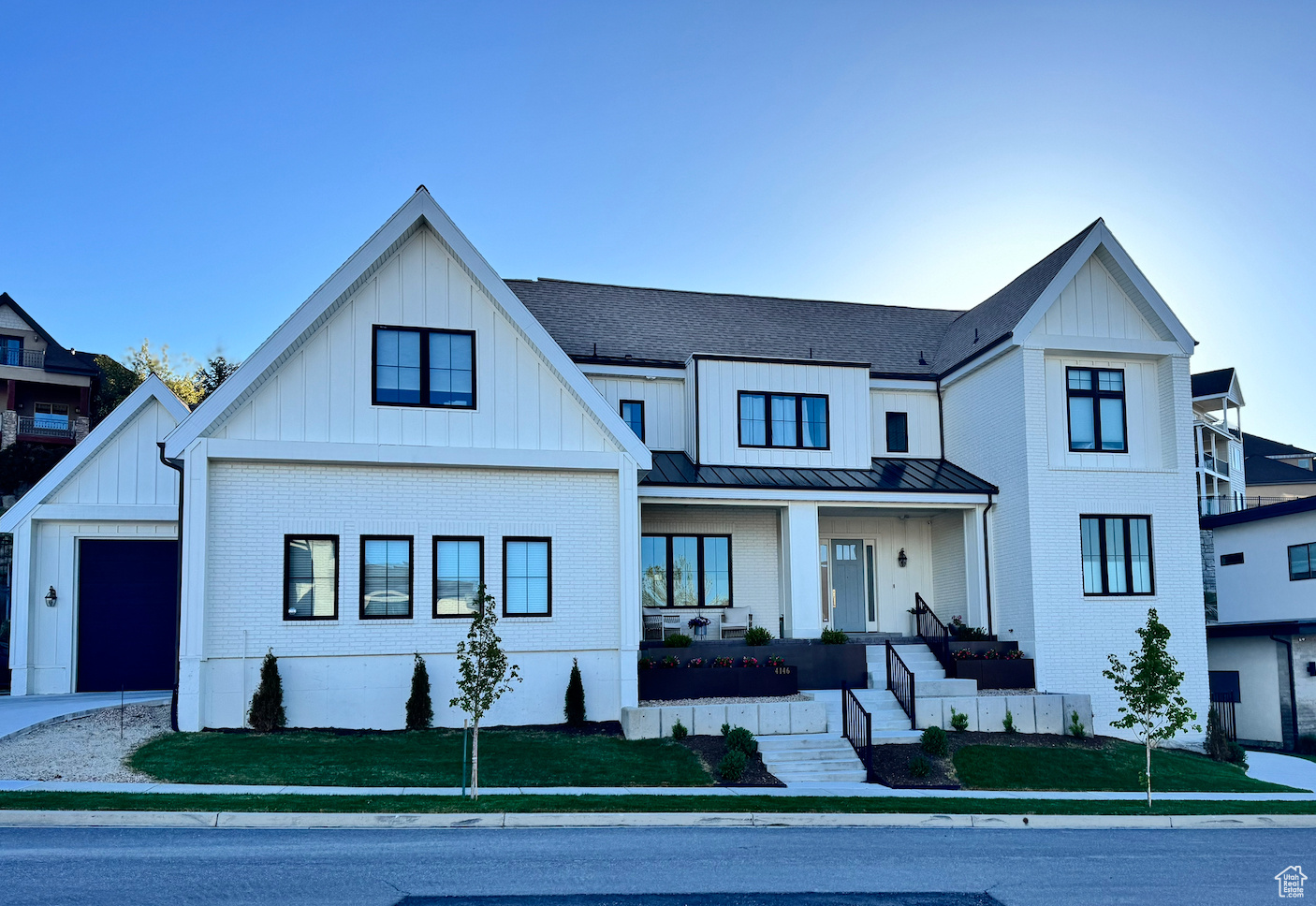Experience luxury living in this stunning 8-bed, 5.5-bath Modern Transitional Farmhouse nestled in the heart of Lehi's Silicon Slopes in a quiet easy to access Traverse Mtn neighborhood. This thoughtfully designed home is adjacent to a quiet park.  Designer details shine throughout from the sleek fixtures to the rich textures. Outside, the curb appeal impresses with white brick, black trim, and copper rain gutters that adds timeless charm. This home comes with 10+ feet ceilings on each level and is perfect for entertaining and everyday comfort. The grand entry welcomes you and your guests just steps away from the open Great Room that has a high 15ft ceiling and a full height gas fireplace area. The Great Room opens up to a private covered patio through a large oversized sliding door for indoor outdoor living. The open gourmet kitchen stuns with an oversized quartz island (12 ft long), custom tile work, high-end appliances, a gas range, and a wide built-in fridge and plenty of cabinet and counter space. Behind the kitchen sits a butler's pantry. The generously sized primary bedroom is located on the main level for easy access and has a private walk-out to the back private covered patio through french doors. The primary bedroom features a beautiful mantel, large ensuite bathroom, soaking tub, spacious walk-in shower, and 'his and her' walk-in closets with a laundry station adjacent to custom built-ins offering plenty of space for all your items. In the lower walk-out level, there are two private bedrooms and a workout room/bedroom, as well as a large family room/game area that connects to a spacious theater room. Adjacent to the theater room is a second kitchen. Upstairs on the second level there is a open tech center/study and a large office/bedroom with two full bathrooms, as well as three bedrooms with high vaulted ceilings. Laundry is convenient with a laundry space on each level for added ease and comfort.  This home blends luxury and functionality, offering the ideal setting for family life and entertaining. Located minutes from Traverse Mountain shopping (Harmon's and Outlet Mall), dining, and tech campuses, this home is ideally situated. Don't miss your chance to own this rare gem in one of Lehi's most sought-after neighborhoods.