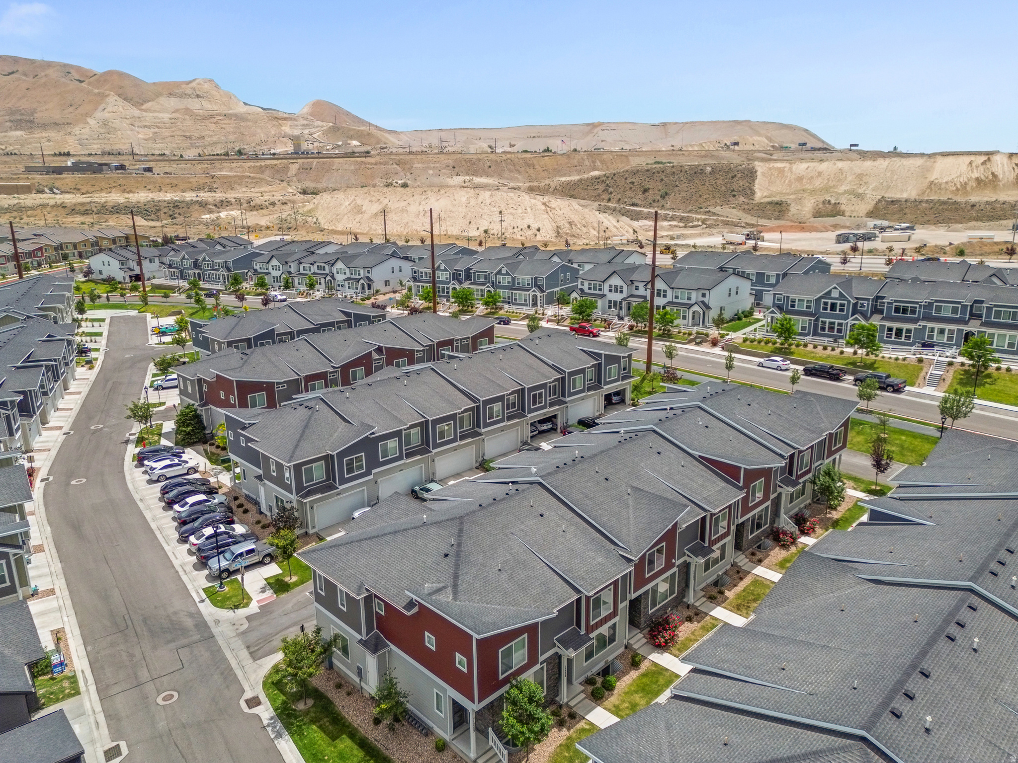 Aerial view showcasing a community of multi-story townhomes with varying exterior finishes, including gray and red siding