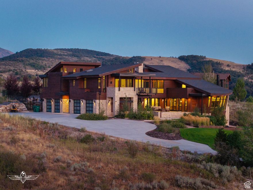 Set high above the valley in the exclusive, gated Hawkins Creek community, this extraordinary estate-crafted by renowned architect Greg Steffensen-is a true expression of refined mountain living. Situated on over two acres, the home captures sweeping panoramic views of Pineview Reservoir and Snowbasin Ski Resort, creating an inspiring backdrop for those drawn to both natural beauty and outdoor adventure. Every element of the home is designed with intention, from radiant heating on the main and upper levels to soaring vaulted ceilings and robust steel-frame construction. Expansive floor-to-ceiling windows flood the interiors with natural light and perfectly frame the surrounding landscape. The great room makes a lasting impression, with exposed beams, rich hardwood floors, and multiple fireplaces that add warmth and elegance. Tailored for both comfort and entertainment, the residence features an indoor sports court, a professional-grade exercise room, and a stadium-style theater. A wine room and sleek bar elevate the experience, while the chef's kitchen-complete with a Wolf six-burner range, dual islands, and custom cabinetry-delivers both form and function. Just off the kitchen, a cozy lounge with a fireplace and two retractable glass walls offers an ideal space for quiet reflection or intimate gatherings. The primary suite is a tranquil sanctuary, showcasing floor-to-ceiling glass sliders that reveal uninterrupted views of the lake and mountains. The suite includes a luxurious walk-in closet and a spa-inspired bath, complete with designer sinks and a ceiling-fill soaking tub for the ultimate in relaxation. A striking glass bridge leads to a private wing featuring an additional bedroom with ensuite bath, a dedicated office, and its own balcony-perfectly balancing privacy with convenience. The home also offers two spacious two-car garages, a fully fenced backyard, and a professionally landscaped patio. Outdoor amenities abound, including a swim spa with a powered cover, a gas firepit for year-round enjoyment, and a heated driveway and patio walkway for seamless winter living. A backup generator ensures peace of mind, and the home is thoughtfully designed to accommodate a future elevator if desired. From its dramatic design to its unmatched setting and amenities, this property stands as a true one-of-a-kind retreat-an exceptional blend of architectural excellence, modern comfort, and mountain elegance. Buyer to verify all.