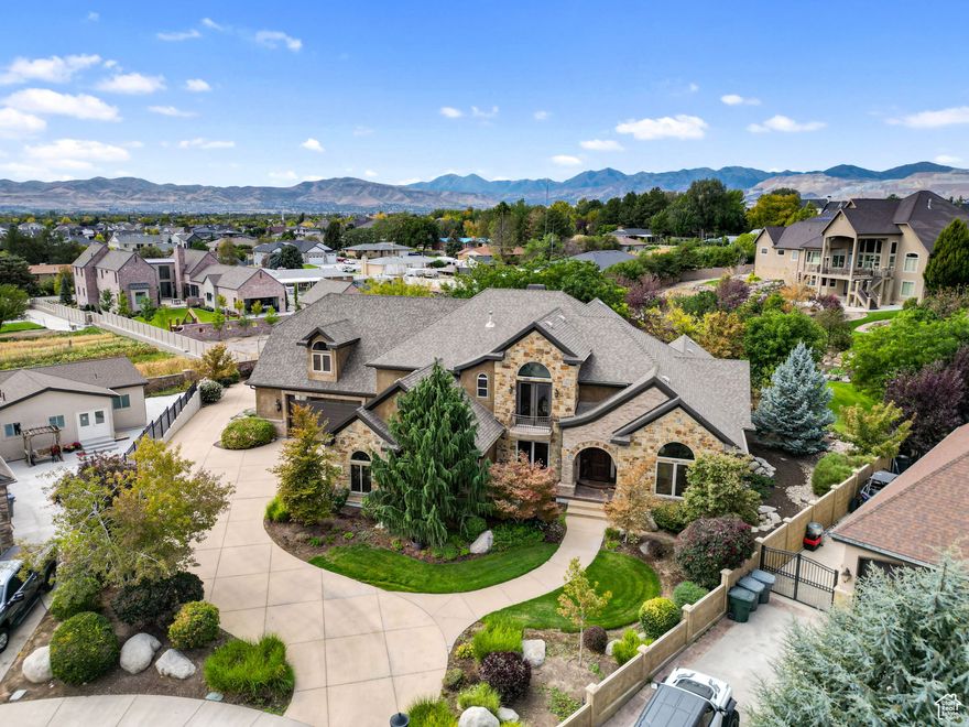 Welcome to Bison Ridge Estates, one of South Jordan's most prestigious neighborhoods, where timeless design meets modern comfort. This custom Tuscany-inspired 2-story estate sits on a rare 0.79-acre lot, offering privacy, luxury, and beautifully curated outdoor living. This home is more than a residence-it's a statement of craftsmanship, comfort, and elegance in one of South Jordan's most sought-after communities. The exterior boasts authentic stone, brick, and stucco with detailed soffit crowns, arched entry, and designer lighting. Step into manicured grounds with a custom timber pergola and fire pit retreat, a handcrafted swing, dry creek bed, and vibrant gardens-all framed by pre-cast fencing for both beauty and privacy. Multiple entertaining spaces include a covered patio, large deck, and walkout basement, creating a seamless indoor-outdoor flow. Inside, more than 8,200 square feet of refined living awaits. Soaring cathedral ceilings and rich finishes set the tone, featuring custom mahogany cabinetry, solid wood doors, built-in shelving, and 10" base moldings. The gourmet kitchen is a chef's dream with Thermador appliances, dual dishwashers, oversized island with detailed millwork, granite counters, and a striking range framed by ornate custom woodwork. The main-level primary suite offers a spa-like retreat, complete with dual stone vessel sinks, oversized walk-in shower with multiple sprays, a soaking tub under arched windows, and a custom-designed walk-in closet. Upstairs, you'll find a spacious family room overlooking the main level, additional bedrooms with private baths, and flexible spaces perfect for work or play. Though not fully finished, the basement is framed and drywalled for a large theater, second kitchen, expansive family area, three bedrooms, and two additional bathrooms-adding incredible potential and value. Every detail was built for efficiency and longevity, including 2x6 exterior framing, full spray foam insulation, dual geothermal heating and cooling, and an interior fire sprinkler system. The home also includes an extra-deep 4-car suspended garage with additional oversized 2-car garage below.