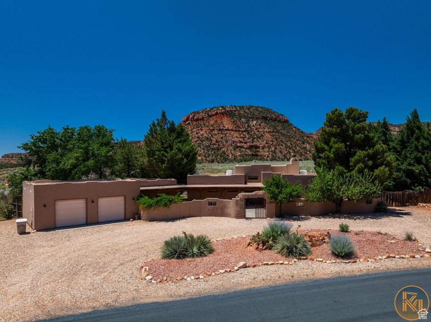 This Santa Fe style, masterpiece is finally on the market. You CAN have it all!!!  Home, Detached Casita (STR) and 2 car Garage. You will Immediately fall in love with its charm, simplicity and elegant attributes. Step through the custom iron gate into the private courtyard and find yourself in paradise. Enter the home and be awe inspired by the gorgeous views through the picture windows and unique custom details. 13' high ceilings. Wood beams. Saltillo tile. Custom cabinetry with large center island complete with butcher block countertop and statement pot rack. Built in refrigerator, oven and gas range. Open living room with a Kiva fireplace. Access to the outdoors from all bedrooms and living areas. Outdoor living at its finest complete with concrete walkways, campfire area and large covered patios. Landscaped to perfection with easy upkeep in mind. Mature trees offer shade & privacy. Fully fenced. RV parking.  Detached casita (currently a vacation rental). Both home and casita are wheel chair accessible. This is the perfect combination of views, acreage, vacation home, rental with an in town location.