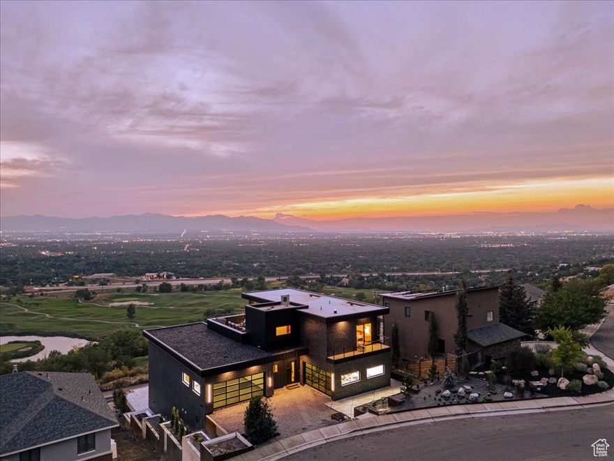 This stunning, modern masterpiece is ideally located in the highly sought-after city of Holladay, Utah, just four minutes to the mouth of Big Cottonwood Canyon and eight minutes to the mouth of Little Cottonwood Canyon. Designed with entertaining in mind, this show-stopping home offers breathtaking views and exceptional craftsmanship. Enjoy a heated driveway, sidewalk, and interior floors, ensuring your space stays cozy year-round and snow-shovel-free. Every detail of this home reflects meticulous design and unparalleled quality. Spanning 7,125 sq. ft., the home features four spacious ensuite bedrooms with walk-in closets and full bathrooms. Additionally, there are half baths on each level, as well as an exterior pool bathroom.  The home has an additional 1,700 sq. feet of deck and patio space. Upon entering, you'll be captivated by the breathtaking views through the floor-to-ceiling windows and expansive living and dining rooms, which provide a serene backdrop for every gathering. The large deck off the primary suite and main living area offers panoramic vistas stretching from the University of Utah to the mountain's peak. The main floor effortlessly transitions into the primary ensuite, where natural light floods the space. The oversized primary steam shower features floor-to-ceiling tile, custom lighting, and a sound system for ultimate relaxation.  The kitchen is at the heart of the home and perfect for entertaining. It is equipped with two dishwashers and double ovens, ideal for large gatherings and memorable occasions. The 300 sq. ft. butler's pantry includes a built-in coffee maker, sink, and ample prep space. Upstairs, you'll find a second entertainment area with a living room and a 1,000 sq. ft. patio that features a fire pit, with the option to design your own outdoor kitchen and BBQ and plenty of seating. The entertainment experience continues in the basement, which boasts a third living area, cigar/game room, and home theater. For fitness enthusiasts, there's a home gym complete with a purified water bottle filler and mirrored walls. The walk-out basement leads to a beautifully landscaped backyard, which includes a 40-ft. saltwater pool, an outdoor bathroom, and a covered seating area. Designed for ease of maintenance, the landscaping is perfect for busy homeowners yet customizable to suit any buyer's preferences.  Enjoy remote access to door locks, lights, and more with the innovative Control 4 system.