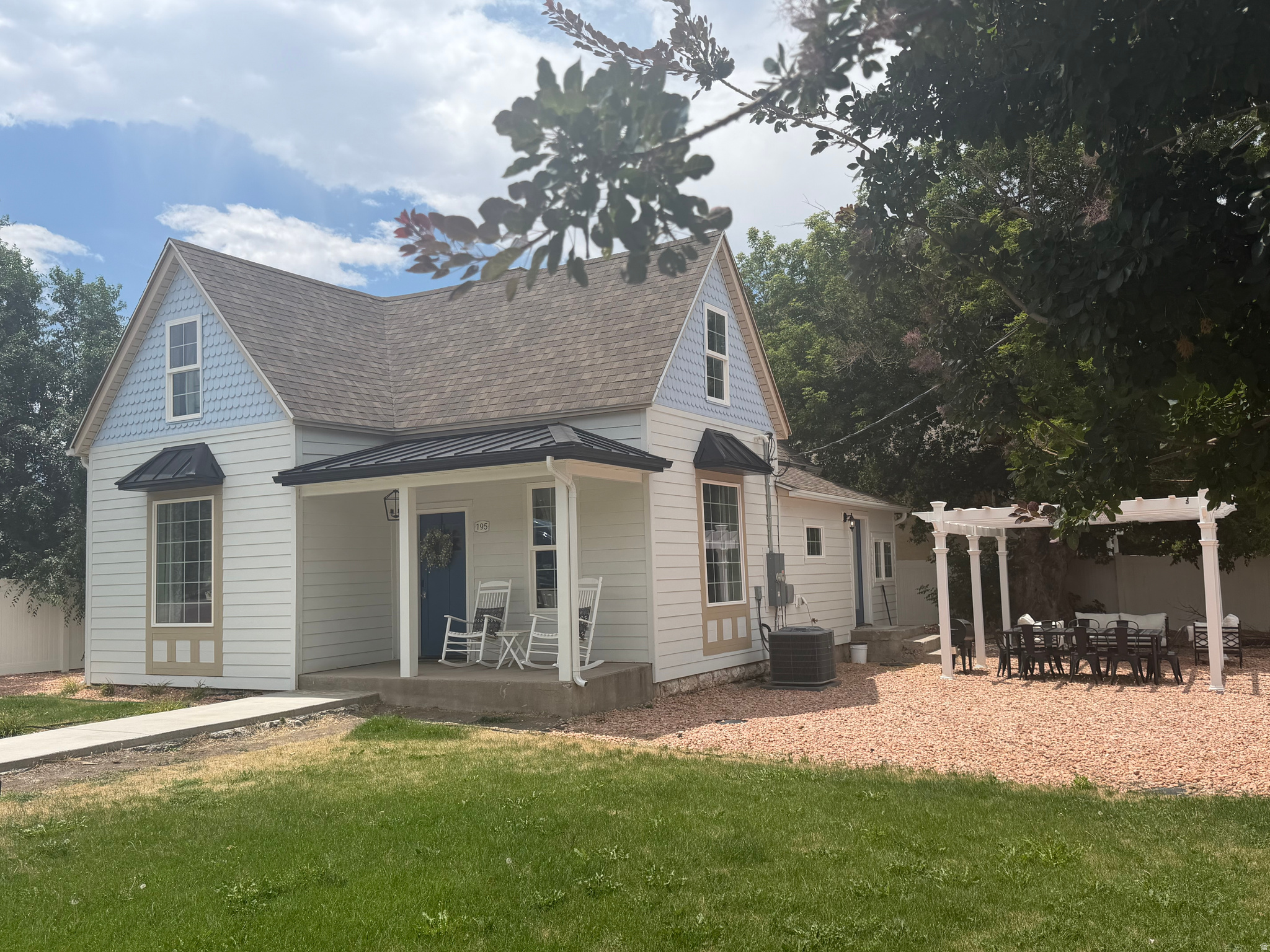White siding exterior featuring a blue door, covered front porch, and a dormer with blue shingles