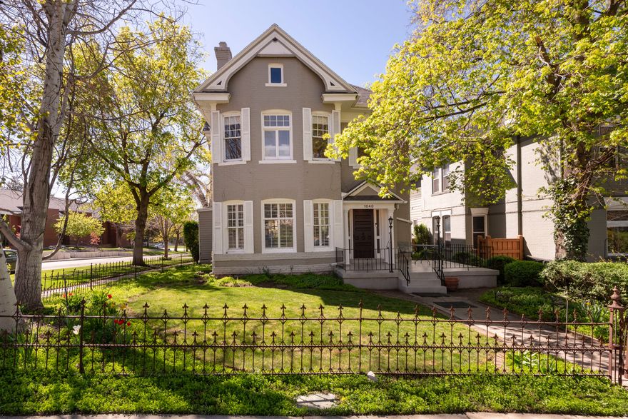 OPEN HOUSE SAT 4/11 1:30-3:30  Classic brick two-story Victorian on a corner lot in one of the Avenues' most desirable historic sections. A grand entry welcomes you with an open staircase, period-style carpeting, and an elegant chandelier that sets the tone for this timeless home. Spacious living room and formal dining area showcase two original fireplaces, gorgeous hardwood floors, high ceilings, and plantation shutters. The eat-in kitchen features a breakfast bar, stainless steel appliances, exposed brick, and abundant cabinetry and opens to a comfortable family room overlooking the backyard patio and gardens, perfect for indoor/outdoor living and entertaining. A cleverly hidden main-floor stackable laundry area with sink and shelving, plus a convenient half bath, completes the main level. Upstairs, you'll find a generous bedroom with walk-in closet, a study/office, nursery, and a full bath with a separate tub and shower. The primary suite features vaulted ceilings, a large walk-in closet, and a luxurious bath with a toilet closet, a separate tub, and a euro-glass shower. The basement offers a clean utility and storage space, plus a recently renovated office or ensuite with private exterior entrance and brand-new  bath, ideal for guests, work-from-home, or flexible living. Outside, enjoy a fully fenced yard with original iron fencing, mature trees, beautiful landscaping, and a lovely backyard leading to the two-car garage. Perfectly located with quick access to the University of Utah, major hospitals, downtown Salt Lake City, and public transit, and only 30 minutes from world-class ski resorts and canyons for year-round recreation.