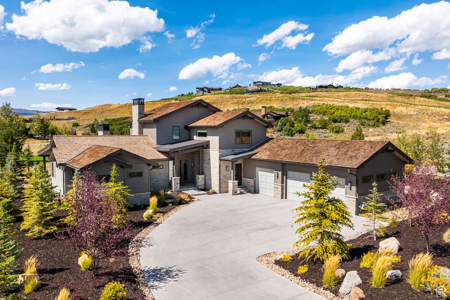 Tucked away on a private cul-de-sac in the prestigious and gated Tuhaye golf community, this contemporary residence offers timeless design and seamless indoor-outdoor living. Built in 2021 on a 0.7-acre lot, the home is just moments from Tuhaye's premier amenities and provides an elegant retreat in one of Park City's most desirable settings. The centerpiece is a 1,308-square-foot covered patio created for entertaining, with dedicated dining and living spaces, a built-in kitchen with Yoder smoker, dual burners, refrigeration, fire pit, sunken hot tub, heaters, automatic shades, and integrated audio. Mature landscaping and a fenced yard with a dog run complete this private outdoor haven. Inside, expansive windows and sliding doors flood the open-concept great room, dining area, and chef's kitchen with natural light. A double-sided stone fireplace between the great room and office anchors the space, while the gourmet chef's kitchen features a dramatic waterfall quartz island, Thermador appliances, dual dishwashers, and a wine fridge, ideal for both intimate dinners and lively gatherings. Two main-level primary suites highlight the home, each opening to the patio. The main retreat offers his and her walk-in closets with custom built-ins and a spa-inspired bath with radiant heated floors, soaking tub, dual vanities, and an oversized shower. A second main level suite provides equal comfort with its own walk-in closet, ensuite bath, and private outdoor connection. The main level also includes a private office, laundry room and a heated three-car garage with epoxy floors, custom cabinetry with fridge, and integrated storage. The home enjoys automatic battery operated shades and a Sonos AV system. Upstairs, a versatile loft with integrated speakers serves as a secondary family room with a wet bar, office nook, and flatscreen TV. Two ensuite guest bedrooms with walk-in closets provide welcoming accommodations, while a full bath, additional stacked washer & dryer, add convenience. A Talisker Club membership is included, offering access to the Mark O'Meara-designed golf course, spa, pools, and dining at Tuhaye, as well as the exclusive Tower Club at Empire Pass and Courchevel Restaurant on Main Street. With year-round recreation and Salt Lake City International Airport just 45 minutes away, this mountain getaway combines space, style, and direct access to all that Park City has to offer.