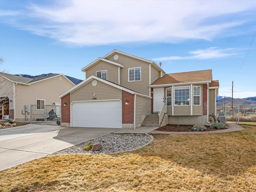 Welcome to 1266 E 850 N in Tooele, where comfort, flexibility, and everyday ease come together in a home designed for real life.  With 4 bedrooms, 2.5 baths, and 1,951 sq ft, this home offers space to spread out while still feeling warm and connected. Natural light pours through the bay window in the dining area, creating a bright spot for morning coffee, weeknight dinners, or quiet moments looking out toward the mountains.  The kitchen opens into the dining space and offers a functional layout with peninsula seating, making it easy to cook, gather, and stay connected. Downstairs, the cozy family room creates a natural retreat for relaxing evenings, movie nights, or simply unwinding at the end of the day.  Upstairs and down, the four bedrooms offer flexibility for a variety of needs such as work-from-home space, hobbies, guests, or quiet retreats.   Outside, the fully fenced yard provides room to enjoy fresh air, entertain, or simply relax. RV parking adds extra convenience and versatility.  This home offers a comfortable setting to create your next chapter in Tooele.  Square footage figures are provided as a courtesy estimate only. Buyer is advised to obtain an independent measurement.
