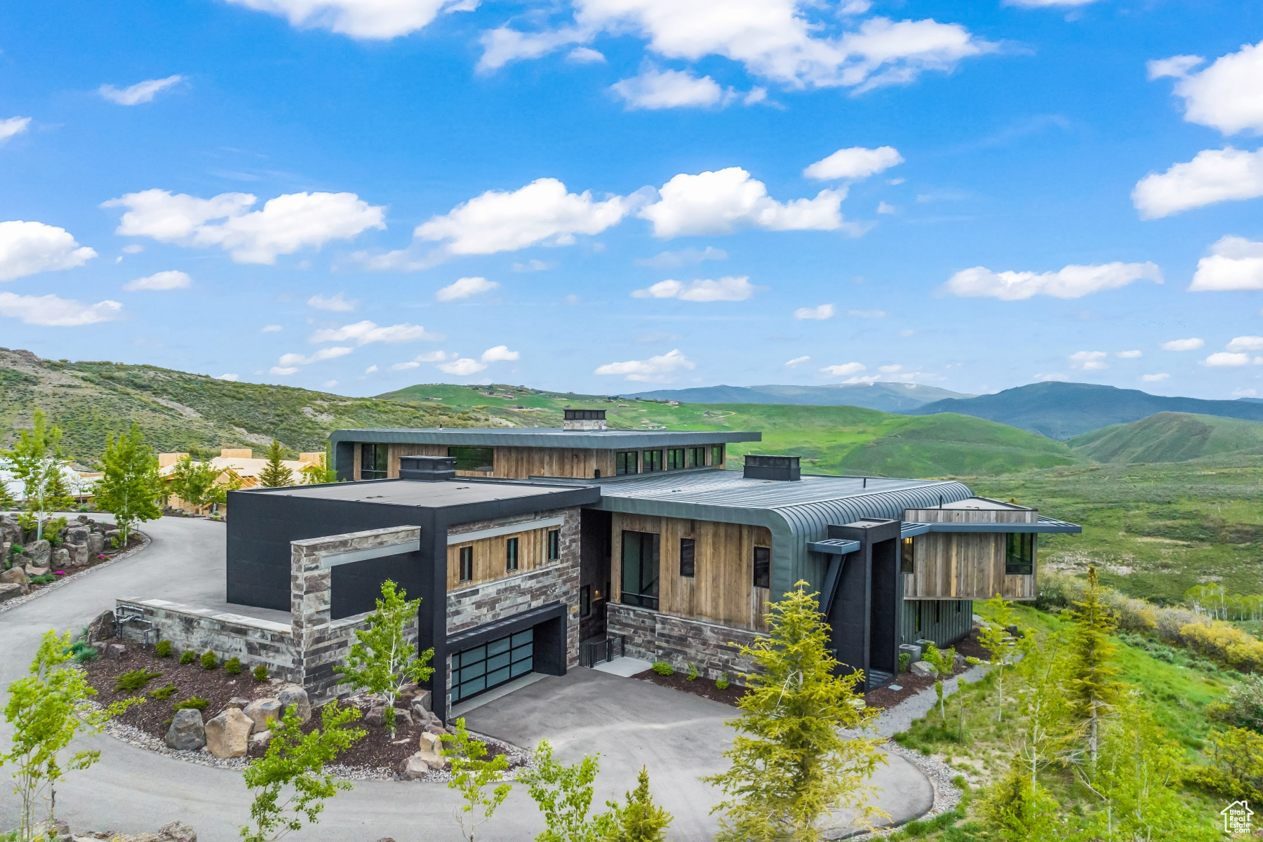 Welcome to 3844 E Outcrop Rd in Aspen Camp, a residence embodying the pinnacle of luxury in Promontory Club. Crafted by architect Clive Bridgewater and built by RS Hardman Building Co., the exterior showcases mirrored 'C' shapes in Zinc with Oklahoma stone and barnwood accents. Upon arrival, a rock wall with flowers leads to enchanting outdoor spaces. Winter living is facilitated by a heated driveway, radiant heat throughout the home, and a grand 5' pivot door from Modern Steel Doors. Step inside to panoramic views of the Uinta Mountain range in the breathtaking entry. The main level features sliding glass walls and 20'+ stained wood ceilings for warmth and comfort that blend seamlessly with nature. Italian Oikos plaster/paint graces prominent features like fireplaces and the wine room. The main level hosts three en-suite bedrooms, including a luxurious primary suite. Ascend to an upper-level office/study space with "airplane views" and a fully heated private deck. Finishes include Ann Sachs tile, Lacava and Stone Forest sinks, Waterworks and Rohl faucets. Radiant heat, Lutron Lighting, and Control 4 automation enhance comfort. The chef's dream kitchen boasts Wolf/SubZero/Cove appliances and a full-size wine fridge. The lower level offers a family room, guest suite, bunk room, and a 2400-bottle wine cellar. An elevator and dedicated dog run add convenience. Outdoor spaces include heated patios, a Twin Eagles breakfast club, grill, pellet grill, and a 9-person hot tub. East orientation ensures fantastic Moonrises and Alpenglow Sunsets, with no direct late afternoon Sun/Heat in the summer months. Furnishings (excluding art) can be included. A full membership is available, providing access to Promontory Club's exclusive amenities. Welcome to a seamlessly blended world of luxury and lifestyle.