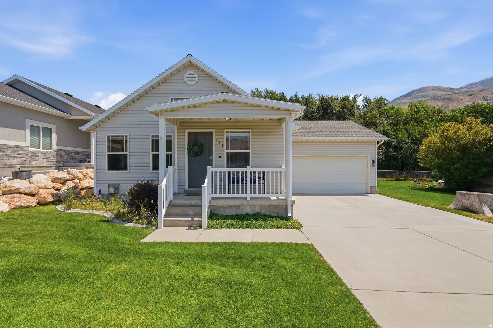 Single-family residence featuring a covered front porch, white siding, and an attached two-car garage