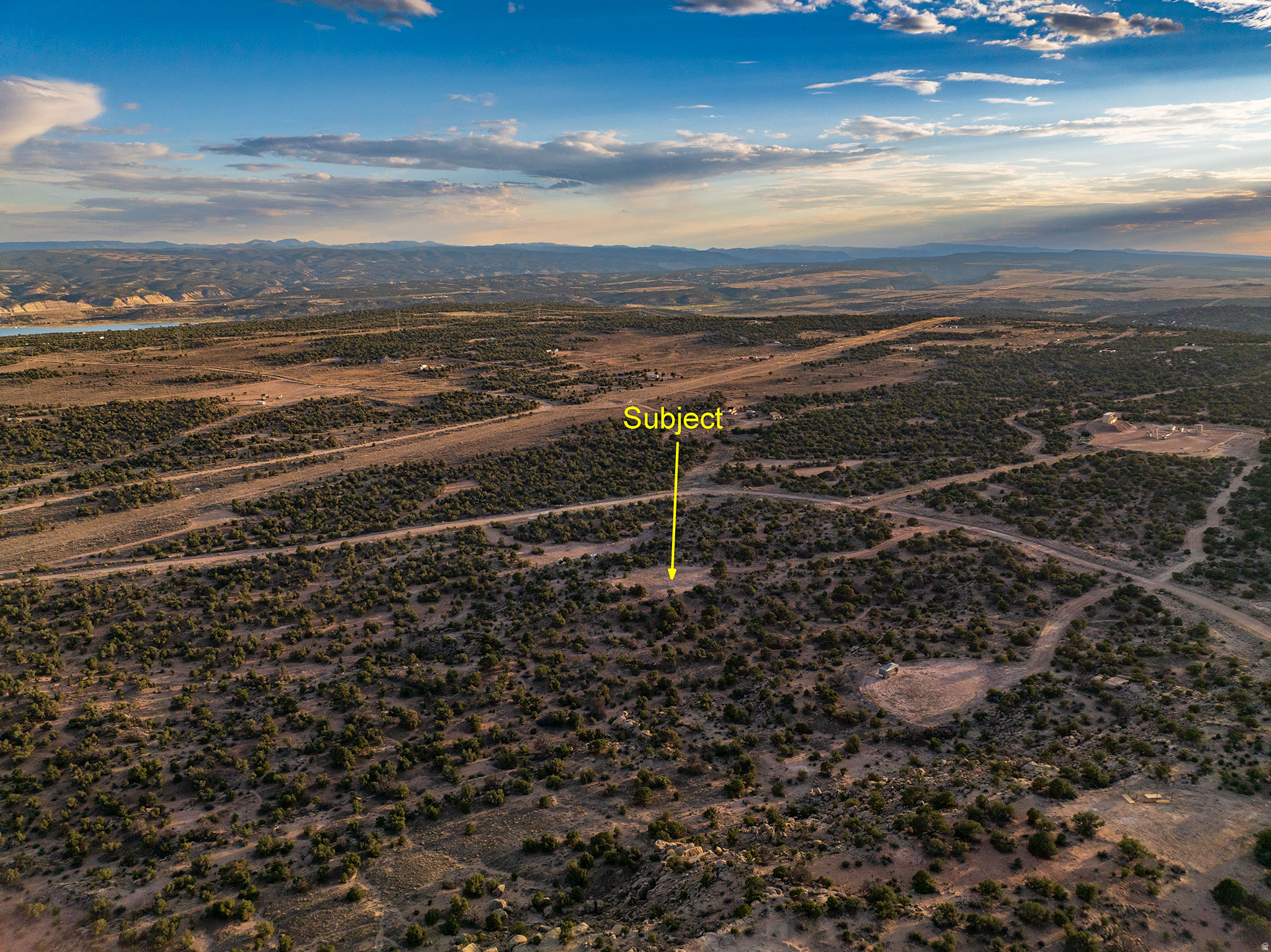 Expansive desert landscape featuring natural scrub brush and dirt roads
