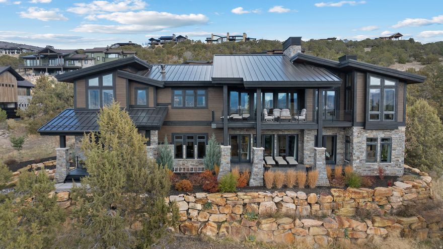 This custom-built modern home is located in a quiet, private area of the Red Ledges gated golf community, designed to take full advantage of the stunning Heber Valley, Mount Timpanogos, and Wasatch Back views. The home combines quality craftsmanship with functional design. Features include an elevator for easy access to all floors, custom metalwork by Finch Welding and Fabrication, Inc., Restoration Hardware lighting and furniture, and thoughtful finishes throughout. The gourmet kitchen is equipped with Sub-Zero refrigeration, Wolf ovens (steam, convection, and microwave), ASKO dishwashers, a Scotsman pebble ice maker, and a butler's pantry for extra prep and storage space.The layout offers a primary suite, two en-suite guest rooms, and a bunk room, along with multiple living areas for entertaining or relaxing. The second level includes a wet bar and theater room.  Lower level has a large flex room ideal for a gym or golf simulator. Outdoor living is a highlight, with four covered decks that provide plenty of space to enjoy the mountain setting. The driveway has radiant heat piping installed (just needs to be connected), and the garage is wired for an electric vehicle charger. With space for over seven vehicles, there's plenty of room for storage or a car collection. Furniture and hot tub are negotiable. Ownership at Red Ledges includes access to world-class amenities-golf, fitness, tennis, pickleball, swimming, and dining-all within a secure, gated community. No need to be on a wait list, Golf or Lifestyle Membership are available, subject to Club membership guidelines. Buyer and Buyer's Broker to verify all information including square footage and acreage