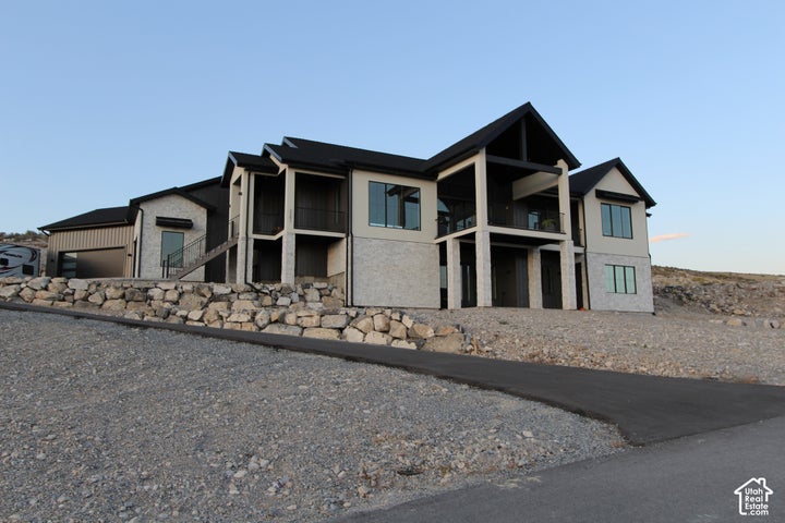 Exterior with a mix of light-colored stone and smooth siding, multiple balconies with dark railings, a dark-pitched…
