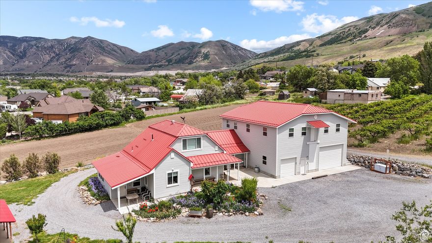 This large home is something very amazing and unique with no element overlooked. The owners went all out on this refurbished historic home, keeping a balance of the original charm and detail work but adding quality modern amenities. The lot has  2.75 acres, large garden open space, large peach tree orchard, and 10 shares of water rights. Outside you will enjoy great mountain views to the east and beautiful sunsets to the west. There is a detached shop for tinkering in or storing things. The detached living unit with kitchen, heating and AC is perfect for an ADU, man cave, she shed, or a detached office/work area.  Inside boasts main floor living with 5 beautiful bedrooms and 3 1/2 bathrooms. The spacious primary suite located on the main floor has its own bathroom, laundry, and garage access.  . Large open kitchen and formal dining area. Lots of storage spaces throughout. There is a large living area above the garage for all kinds of uses. The area has a full kitchen, bathroom, bedroom and large open area, perfect for an ADU, gatherings, work, the possibilities are limitless. The oversized garage is fully finished, has a thermostat controlled heater, 11' tall pull through doors, and lots of storage shelving.