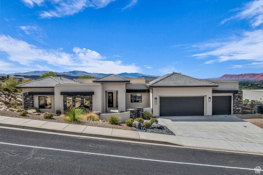 Perched in Southgate Hills, this warm contemporary home captures panoramic views of St. George, Green Valley, & the surrounding mountains. Inside, you'll find a bright open-concept layout w/ ceiling-height windows, sleek gas fireplace, & a gourmet kitchen w/ granite countertops, hidden pantry, and built-in beverage station. The primary suite features a spa-like bath & a custom walk-in closet with natural light. A guest room w/ courtyard entry is ideal for visitors or flex use. Step outside to enjoy a custom louvered patio with drop-down sunshades, gas fire pit, & built-in BBQ-all surrounded by low-maintenance xeriscaping. The 3-car garage includes epoxy floors, built-ins, & overhead storage. No HOA. Minutes from golf, trails, & dining-offers refined desert living w/ incredible views.