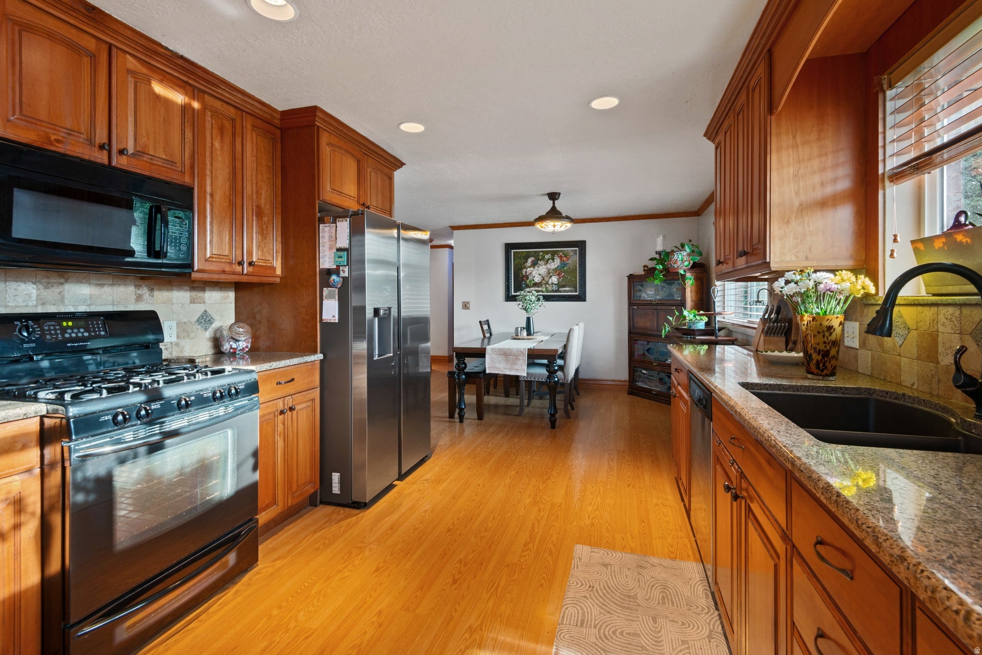 Full kitchen featuring wood-finish cabinetry, stainless steel appliances, granite countertops, and stone tile backsplash
