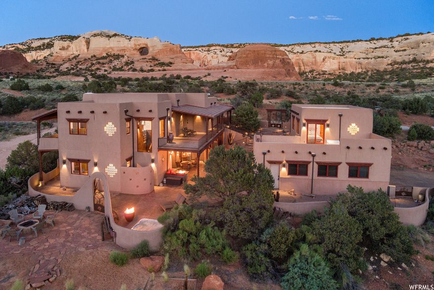 ESCAPE TO YOUR DESERT RESORT- Here is your destination estate for adventure in Southeastern Utah. A convergence of peace, artistic expression, custom detail, luxury, rugged beauty, and fun...in one incredible package. Bring your bags, bring your toys, stop at the grocery- then land  once you are here, you won't want to leave.  Over 5 acres of desert landscape adjoining additional deeded open land allows for a setting of absolute privacy and intimacy with the surrounding vistas. With seven patios covering over 4,300 square feet, the outdoor living is as incredible as the southwestern interior. Celebrating the local surroundings with custom paint finish on the American Clay walls, travertine tile that flows in patterns equal to the neighboring arroyos, celestial hard wood vigas that broaden the awe-inspiring dining room above the wall to ceiling windows, stacked stone, and kiva fireplaces. Thermador appliances, including a built-in espresso machine, accommodate this exceptional kitchen with alder cabinets offering plentiful storage, living edge granite counter tops, as well as the custom hammered copper features- island inlays, dual bay sink, and vent hood. The main bedroom suite has access to the outdoor kitchen patio with fireplace and additional access to the surrounding covered patios with massive fire features. Two additional guest en-suites, an extra bedroom, music room, game room, theater room and lower-level kitchenette/wet bar with hammered nickel sink and ice maker, all allow for spacious, and entertainment filled gatherings. On the other side of the stamped concrete and beautifully lit courtyard is the guest casita with one-bedroom, full bathroom, kitchenette, and private covered patio, as well as a view balcony. Soak your bones in the sunken hot tub, adjacent to more fire features, the flagstone fire pit, horseshoe pit, and surrounding area to set up your frisbee golf course. This desert escape includes most of the base furnishings with a few exclusions, as well as a few minor art inclusions.  The attached oversized garage has over 1,100 square feet of space for your toys. Ready to escape? Square footage figures are provided as a courtesy estimate only and were obtained from images. Buyer is advised to obtain an independent measurement.