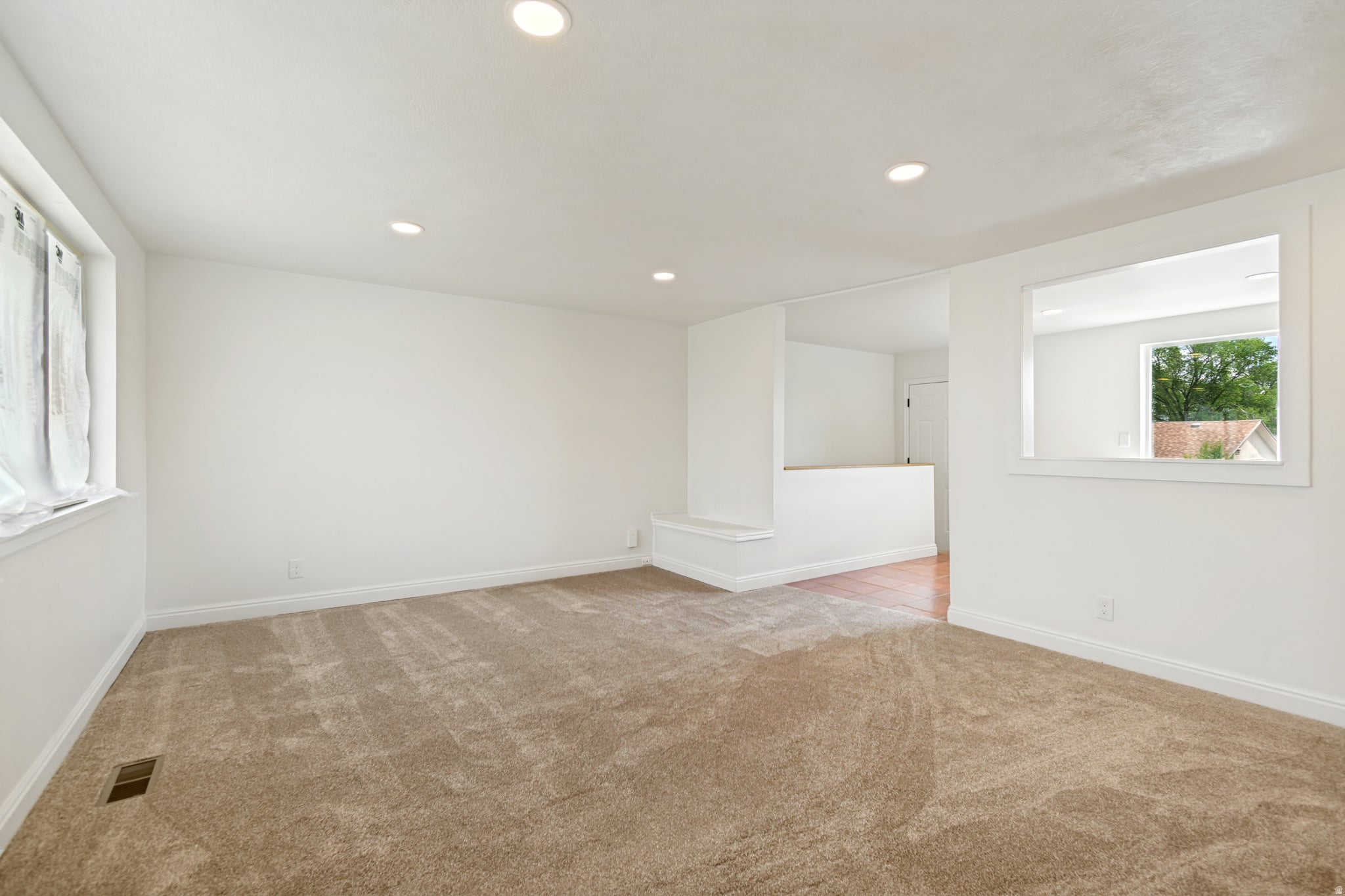 Recessed lighting, neutral color palette, wood-finish flooring, half-wall partition, and an interior pass-through window