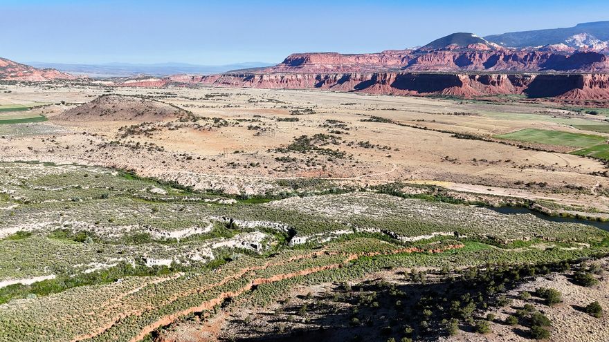 This 120-acre+ property located on the Teasdale Bench in Wayne County offers a combination of elevated terrain, expansive views, and practical improvements that support a variety of potential uses. The setting is defined by its position on a high mesa, where much of the land is relatively flat with gentle rolling contours. The landscape features a mix of open ground, sage, cactus, and scattered pinyon pine and juniper trees, covering more than 30 acres of the property.  From multiple vantage points across the parcel, there are clear views of surrounding natural landmarks, including the Boulder Mountains to the south and the distinctive red rock formations and bluffs that characterize the region. The northern portion of the property drops approximately 100 feet, creating a natural edge where the Fremont River can be seen below. Along the southeastern boundary, views extend toward Cottonwood Creek, an area that supports local wildlife activity.  Wildlife presence on and around the property includes mule deer, small game, coyotes, and foxes. A neighboring pond contributes to seasonal waterfowl activity, including ducks and geese, during the winter months. The combination of vegetation, water proximity, and varied terrain supports a diverse habitat.  Access to the property is convenient yet maintains a sense of separation. The parcel is located just over 600 yards from the paved Teasdale Bench Road and can be reached via the Teasdale Powerline Road and other established routes. The nearby town of Torrey is only a short drive away, providing access to basic services, dining, and supplies while maintaining a rural setting.  Infrastructure elements are already in place to support future use. A well permit, identified as WR 95-5525 with 1.48 acre feet of underground water rights, has been secured. Existing roads across the property provide internal access and flexibility for site planning.  These features allow for multiple potential building locations depending on preference for views, access, or proximity to utilities.  The property is bordered in part by public land managed by the Bureau of Land Management, which contributes to the sense of open space and limits the likelihood of nearby development. The area is also known for its low levels of light pollution, providing clear night skies and visibility of stars.  This parcel presents an opportunity for those seeking a recreational property, a residential setting, or a long-term land holding in southern Utah. Its combination of acreage, location, access, and existing improvements supports a range of possibilities while maintaining the natural characteristics of the region.