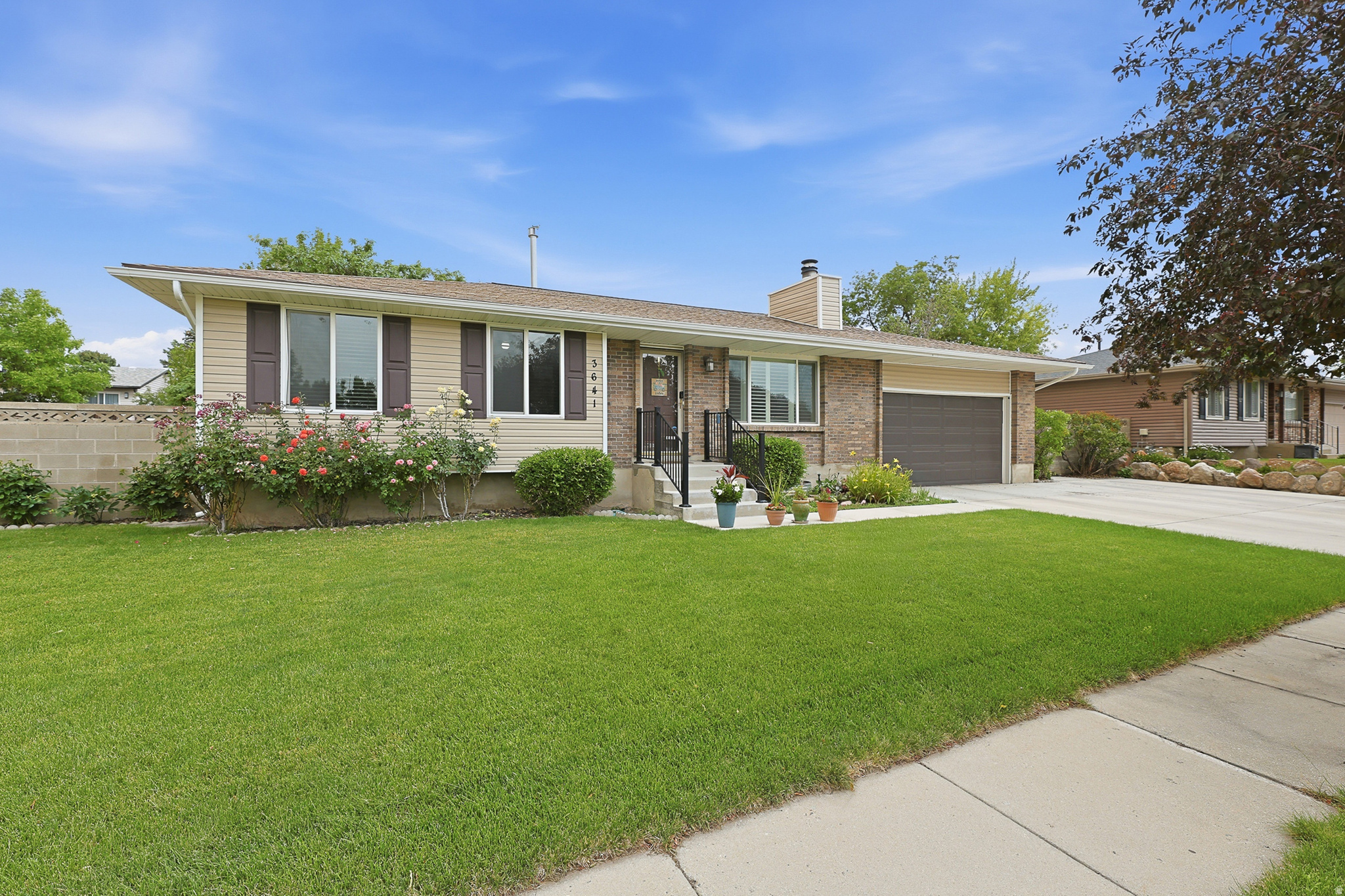 Ranch-style exterior featuring a brick and siding facade, a front lawn, a paved driveway, and an attached garage