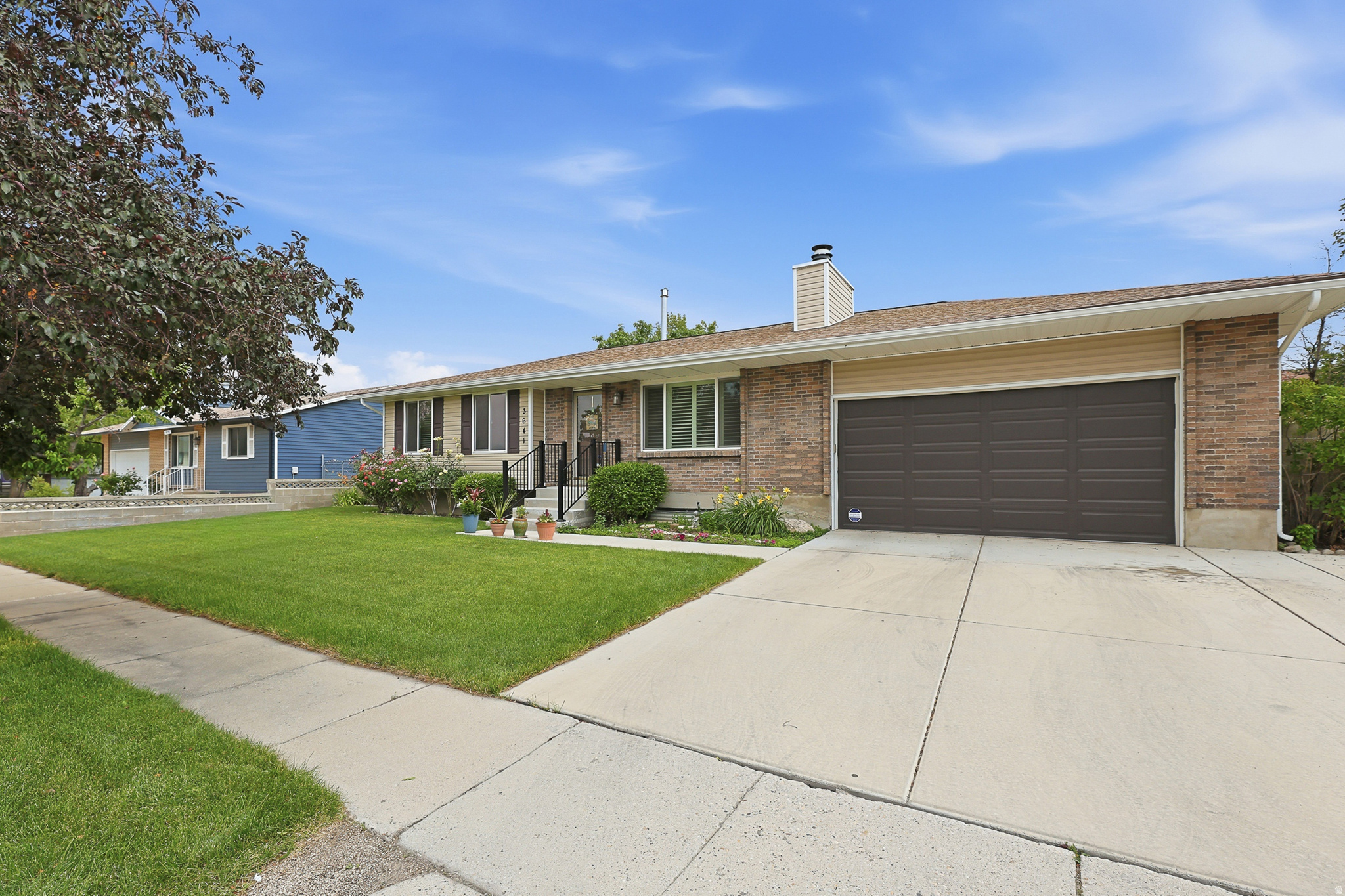 Brick facade residence with a two-car garage, mature front lawn, and concrete driveway