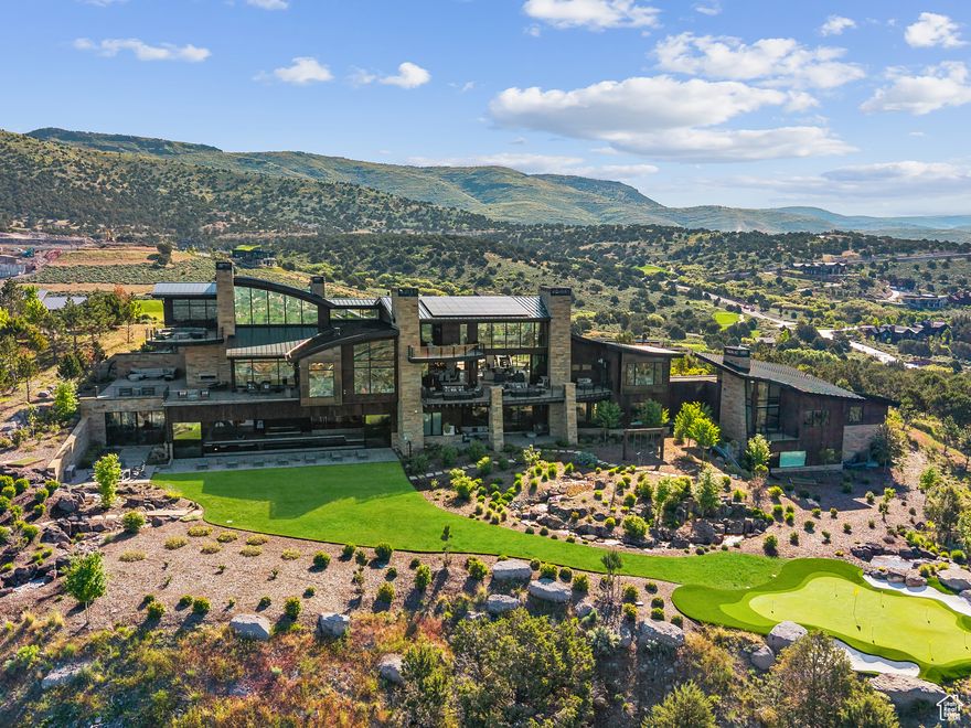 Elevated above the rest, this striking mountain estate claims one of the most commanding ridgelines within the coveted Red Ledges gated community, offering panoramic views that sweep across the Wasatch Range and Heber Valley. Designed by visionary architect Michael Upwall and brought to life by the renowned Shawn Johnstun, this exceptional residence blends bold architectural form with the warmth and function of a true legacy retreat. Just 15 minutes from Deer Valley Resort, the home balances alpine seclusion with resort-level accessibility. Nearly 21,000 square feet of thoughtfully designed living space offers an extraordinary backdrop for both intimate moments and grand entertaining. Every detail has been considered, with timeless materials, flawless craftsmanship, and seamless indoor-outdoor flow throughout. World-class amenities include an indoor sport court, a fitness suite with private sauna and steam rooms, a 50-foot indoor pool and spa, and a 2,000 square foot rooftop putting green with sweeping alpine vistas. A state-of-the-art indoor golf simulator ensures year-round play, no matter the weather. Expansive terraces with fire features and built-in audio create the perfect setting for relaxed mountain evenings and unforgettable events. The home offers 7 bedrooms and 11 bathrooms, including a serene primary wing, a two-bedroom private guest casita with full kitchen and garage, and a whimsical custom bunk room designed to host generations of guests in style. Offered fully furnished with custom-selected pieces and artwork, the interiors are ready for effortless move-in. The grounds are as extraordinary as the interiors, with cascading water features, massive Wyoming boulders, manicured lawns, and a private 75-yard par 3 golf hole with an infinity-edge green. It's all surrounded by the natural beauty and stillness of the mountain landscape. Red Ledges premier club amenities include the Jack Nicklaus Signature Golf Course, ski and adventure clubs.