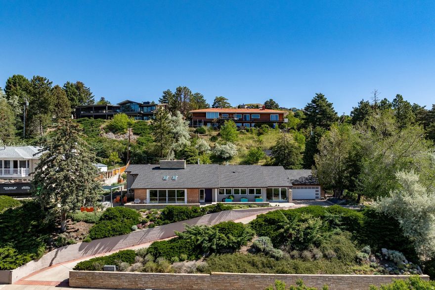 "In 2017, AJC Architects reimagined this understated modern mid-century rambler into one of the Upper Avenues' most compelling architectural renovations. Perched on the north side of Aloha with sweeping mountain and valley views, this home masterfully blends timeless mid-century design with elevated modern living. Elegant yet comfortable, the spacious main-floor living area is designed for effortless entertaining, anchored by an original 18-foot sandstone wall, exposed wood beams, custom built-ins, bench seating, and a gas fireplace. South-facing sliding glass doors open to a private patio, seamlessly connecting indoor and outdoor living. The home office features a hidden wet bar - a nostalgic nod to the sophisticated entertaining culture of the 1950s.Thoughtfully designed, the kitchen combines beauty and function with solid wood Peppertree cabinetry, quartz and Caesarstone countertops, floating shelves, glass block backsplash, stainless steel Miele and Sub-Zero appliances, double ovens, pullout drawers, under-cabinet lighting, on-demand hot water faucet, abundant natural light, and a sink perfectly positioned to capture the views. A nearby walk-in pantry adds convenience, while the nostalgic pass-through window connects seamlessly to the formal dining room. Beautiful hardwood floors run throughout, while all stone tile flooring is enhanced with radiant heat. The spacious primary suite offers a private retreat with backyard access, built-in dresser, generous closet with custom shelving, dual-sink vanity, jetted tub, walk-in shower, and separate water closet. The lower level includes a private bedroom suite, egress windows, plus additional flex space which can be used as a bedroom. Additional highlights include a spacious main-floor laundry room, mudroom, original doorbell chimes, pocket doors, art niches, custom wood handrails, whole-house water filtration system, and seismic retrofitting. Outdoor living is equally impressive with planter boxes, a water feature with gas fireplace, aluminum pergola with canvas awning, and storage shed included. The garage has a 220V outlet. Close to private neighborhood swimming pool, public parks, pickleball courts, University campus and airport.