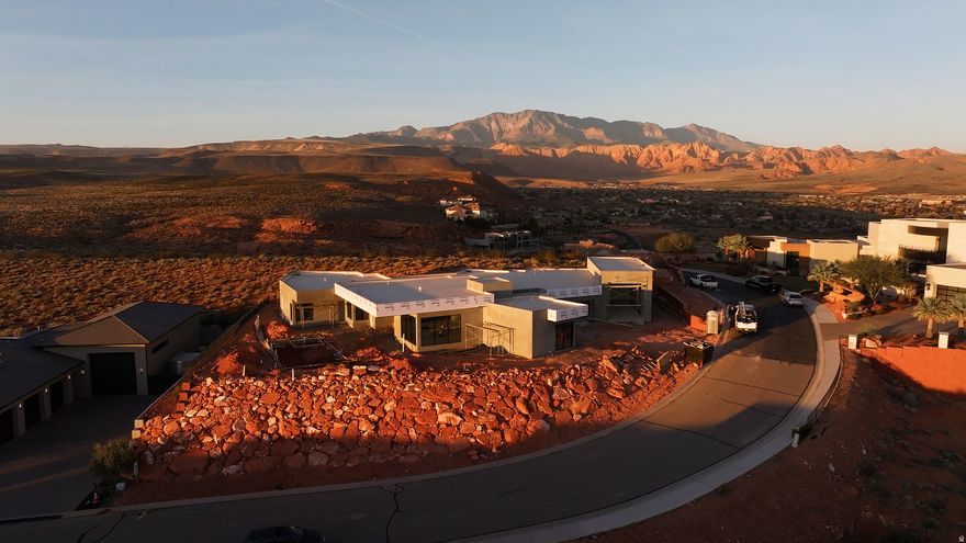 Perched near the top of the gated enclave- Westgate Hills, this single-level home takes in sweeping views of Pine Valley Mtn, sandstone cliffs, city lights & crimson ridges to the south. Set on a private -acre lot, it features a 43-ft RV garage w/12'x14' door, 3-car garage & RV pad. Outdoor living shines w/ heated pool, spa, waterfall feature, shamu shelf & auto cover. Inside: 5 beds (5th as office w/view), glass media room, private guest suite with incredible views, a chef's kitchen w/ custom cabinets, high-end countertops & appliances, large working pantry w/southern mountain views + an additional storage pantry. Primary retreat has a large window that perfectly captures Pine Valley Mtn views, has a spa-like bath & spacious closet w/ laundry hookups. Est. completion Jan 2026.