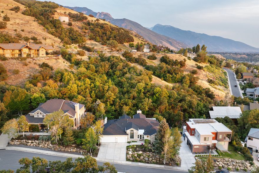 Discover a rare opportunity in the coveted Canyon Cove neighborhood at the mouth of Heughs Canyon with this custom-built rambler by Ron Christiansen Builders. Nestled in a quiet cul-de-sac and built upon solid rock, this 5-bedroom, 4.5-bath home offers over 5,200 sq. ft. of stately interior living with vaulted ceilings, skylights, inlayed tile designs in the wood flooring, and custom arches throughout. Expansive windows frame the surrounding wooded beauty, while the versatile layout includes a wet bar in the basement for entertaining. The master en-suite offers a generous footprint with a spacious double vanity, walk-in closet, and direct access to a private sunroom retreat. Outside, beautiful gardens and water features in both the front and back enhance the natural setting, perfectly complementing the seasonal creek that runs through the backyard. Modern upgrades include a new roof (2023), tankless water heater, triple-pane windows, heated driveway and sidewalks with automatic snow sensors, and gutter heating cables. With two fireplaces, a 3-car garage, and incredible bones, this timeless home is the perfect canvas to remodel into your dream retreat in one of Salt Lake's most desirable neighborhoods.  Please note: Google Maps may display incorrect driving directions for this address. For accurate navigation, use address 3582 E Heughs Canyon Cir, Holladay, UT 84121