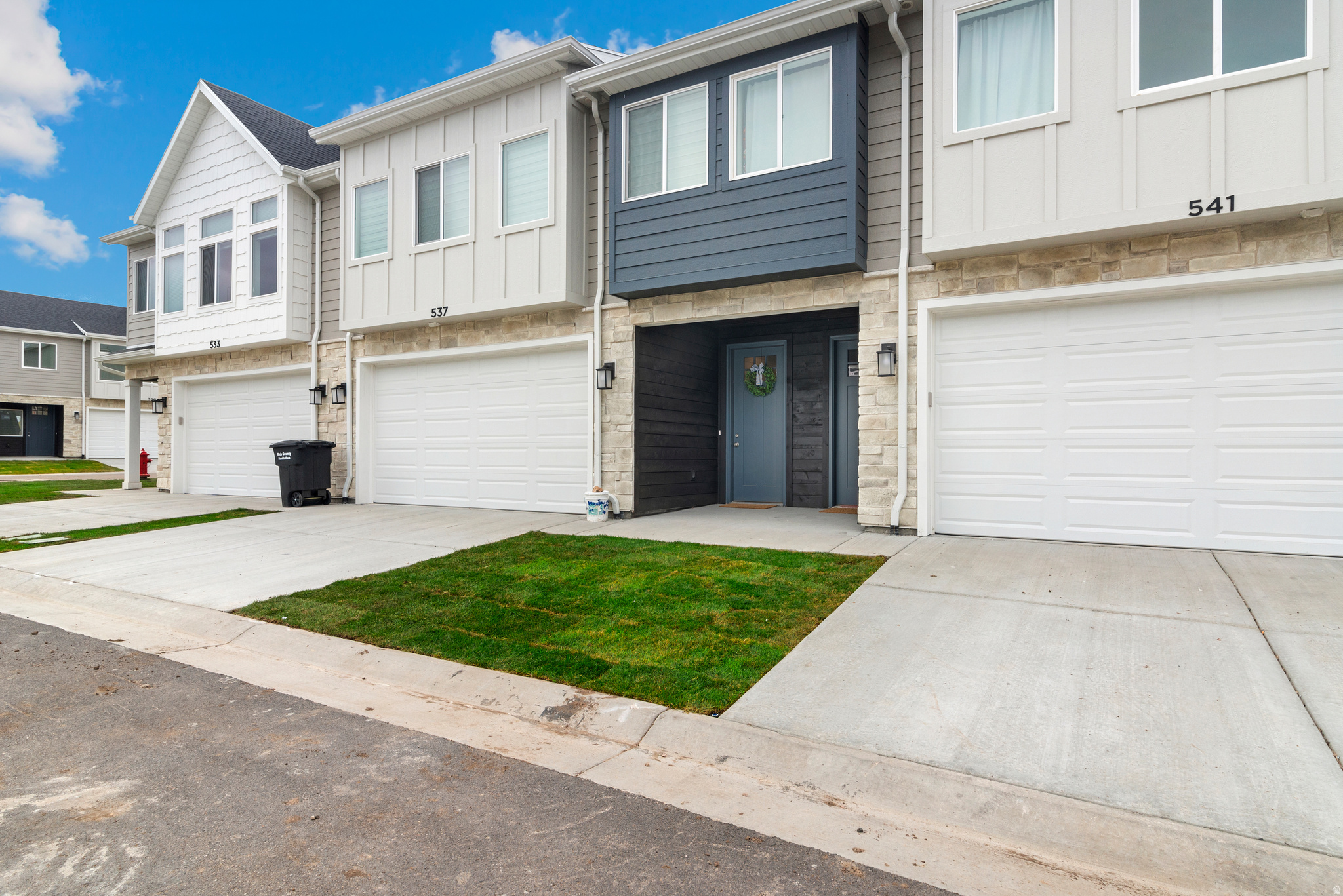 Modern townhome exterior featuring multi-toned siding, stone accents, and a two-car garage
