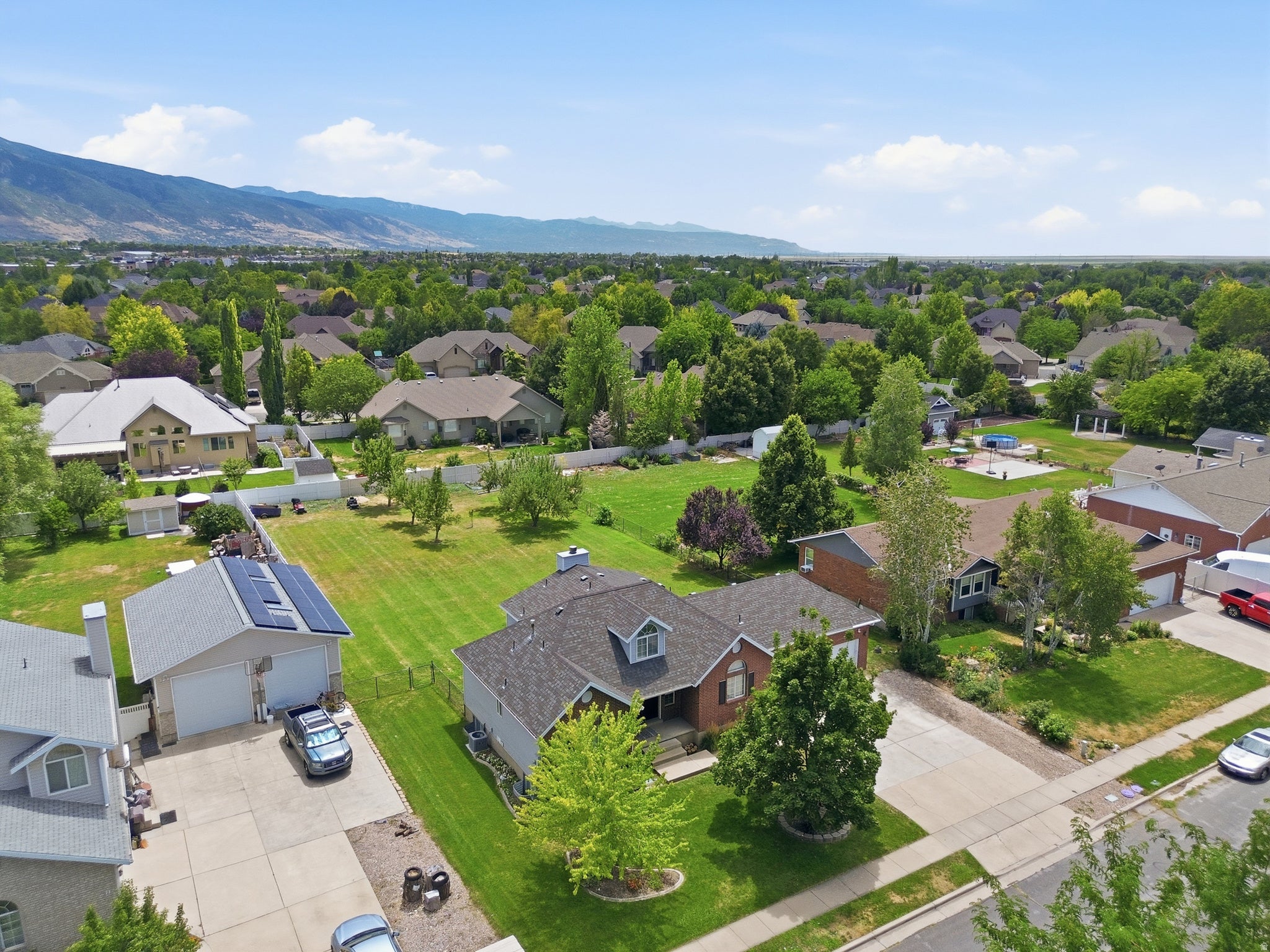 Spacious residential property featuring a large green lawn, mature trees, and a paved driveway