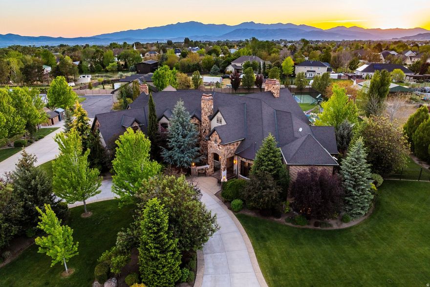 Experience a truly rare estate opportunity in the heart of Highland, offering 3 pristine acres of fully equipped horse property with breathtaking, unobstructed views of Mount Timpanogos and the surrounding Wasatch peaks. Tucked away on a quiet dead-end street with minimal traffic, this extraordinary 15,893 SF property combines luxury living, recreation, advanced technology, and self-sufficiency in one remarkable setting.  The grounds are designed for both lifestyle and function, featuring a barn with two horse stalls, stable, and expansive pasture, along with a chicken coop for added rural charm. The park-like backyard is meticulously maintained and showcases mature landscaping, a tranquil 30-foot waterfall, outdoor fireplace, and mature fruit trees producing nine different varieties of fruit. A large, fully irrigated garden with raised garden beds and a powered greenhouse with an automated roof for temperature control further elevate the property's unique blend of luxury and sustainability. Resort-style amenities include a swimming pool with diving board, in-ground trampoline, tennis court, gazebo, and stunning outdoor spaces that perfectly complement the natural beauty of the area.  Inside, the home offers an impressive 8 bedrooms and 10 bathrooms, highlighted by a spectacular circular entryway with custom inlaid wood and tile. The gourmet kitchen is built for entertaining, showcasing Wolf appliances, a large pantry, butler's pantry, and dual dishwashers.  The thoughtfully designed layout includes incredible flexibility with a fully functioning 3-bedroom apartment on the east side of the main level that can seamlessly integrate with the home or be secured as a private space. Additionally, a full 1-bedroom, 1-bathroom mother-in-law apartment includes its own kitchen, living room, and laundry-ideal for guests or multigenerational living.  Luxury amenities abound, including a stunning home theater with new projector and theater equipment, expansive private gym, and racquetball court. The main level features a cozy wood-burning fireplace, while the primary suite is privately situated in its own wing, complete with a spa-like bathroom, separate closets, and a private deck overlooking the serene waterfall and backyard.  Designed with comfort, convenience, and preparedness in mind, the estate features Sonos audio throughout the home and pool area, full-property WiFi and networking coverage across all three acres, Ring security systems throughout the property, and a Rachio automated sprinkler system. Two oversized water storage tanks inside the home, buried propane tanks, two Generac backup generators, and a basement wood-burning stove with cooking burners provide exceptional peace of mind and self-sufficiency.  Car enthusiasts and hobbyists will appreciate the attached 4-car garage plus an additional oversized detached shop accommodating 8 more vehicles. The fully heated shop includes oversized doors designed to easily accommodate boats, trailers, or RVs.  This is a one-of-a-kind property offering luxury, privacy, technology, recreation, and unmatched amenities-all in a premier Highland location.