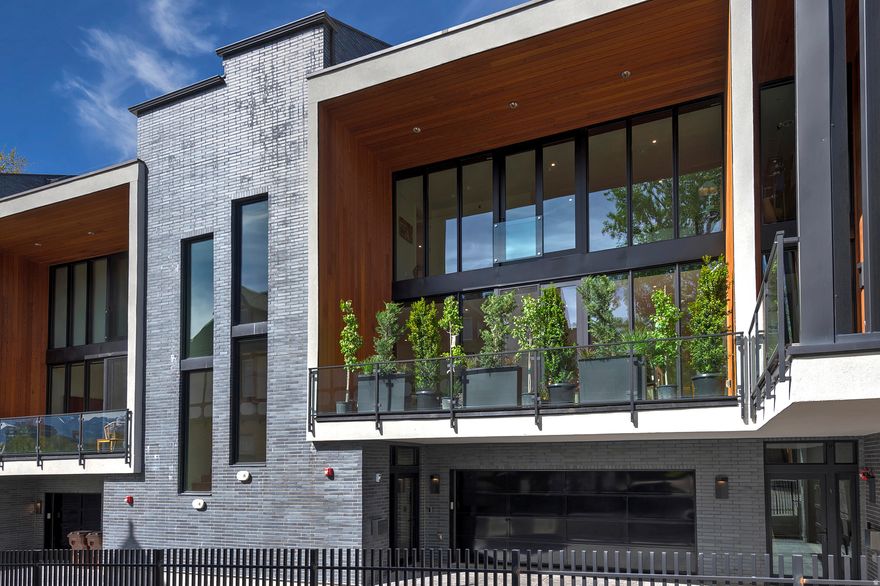 Modern luxury townhome set along the iconic Historic South Temple, offering a blend of architectural design and urban living just minutes from the University of Utah, downtown, shopping, and fine dining. Built to commercial standards, the residence is defined by expansive floor-to-ceiling Windsor windows that flood the home with natural light, engineered walnut flooring, and a thoughtfully designed open layout. A true statement piece, the custom 16-gauge stainless steel floating staircase features a perforated design inspired by the Wasatch Mountains. The chef's kitchen is appointed with a premium Bosch appliance package, commercial-grade Mirlux high-gloss cabinetry, quartz countertops, and a marble and stainless-steel patterned backsplash. Floor-to-ceiling glass doors extend the living space to a private 163 sq ft deck, wrapped in cedar for a warm, modern contrast. The upper level offers a well-appointed primary suite, secondary bedroom, and full bath. The crowning feature is the expansive rooftop deck, featuring over 590 sq ft of elevated outdoor living space designed for both relaxation and entertaining, complete with Trex decking, turf, and a steel pergola. All while offering sweeping mountain, capitol, valley, and sunset views. Additional high-end features include a Lutron lighting system, brand-new high-efficiency HVAC, an in-line water heater, enhanced sound insulation with 16" partition walls between units, and a garage wired for electric vehicles.