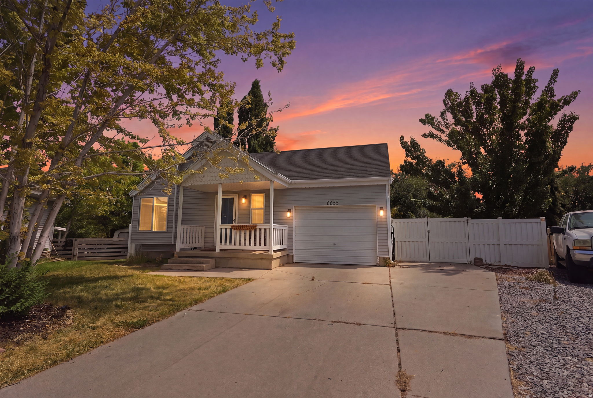Gray siding exterior with white trim, featuring a covered front porch with white railings, and an attached single-car garage