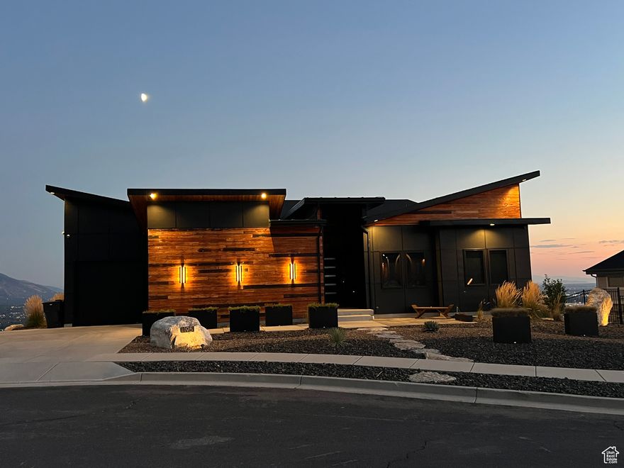 Stunning Modern Home with Panoramic Views. Welcome to a one-of-a-kind, custom-designed home where luxury meets innovation. Perfectly perched to capture breathtaking, unobstructed views of the majestic mountains, sparkling city lights, unforgettable sunsets, and the shimmering waters of the Great Salt Lake and Willard Bay, this home offers a lifestyle like no other. Featuring 3 bedrooms and 2.5 bathrooms, the main level boasts a spacious master suite complete with his and hers walk-in closets-ideal for any shoe lover-and a spa-like en suite with a standalone soaking tub and double walk-in shower. Crafted with unique Shou Sugi Ban wood accents both inside and out, this home is as visually striking as it is thoughtfully designed. Discover the charm of two hidden doors, adding character and a touch of mystery. The chef's kitchen includes a gas range, soft-close cabinetry, walk-in pantry, 12 seating island and a layout made for entertaining. The open-concept living space flows effortlessly - perfect for family gatherings. An outdoor spiral staircase leads to a private rooftop terrace with a gas grill hookup, where you can soak in even more of the sweeping views. Enjoy year-round comfort with radiant heated concrete floors, as well as never having to shovel snow again with sensor activated heated driveway, walk, and porch. Feel the open space living with featured 10-foot ceilings on both levels and custom 8 foot solid wood walnut doors. Designed with sustainability and comfort in mind, this home has smart features, plus five strategically placed mini splits providing energy-efficient heating and cooling throughout-no ductwork. To fully embrace its unbeatable location, the home is outfitted with 13 oversized 6' x 8' energy-efficient windows, perfectly positioned to frame the incredible valley views and flood the home with natural light. The 2-stall garage features extra-tall ceilings, with the ability to accommodate car stackers for auto enthusiasts. Additional features:  Custom rustic walnut cabinetry and doors throughout Leathered granite countertops  Xeriscaped yard with natural gas fire pit, three fire boxes, three sphere water fountains with a holding pond  Hot tub ideally positioned for watching sunrises, sunsets, and stargazing under the open sky.  Smart home features manageable by apps and voice commands Unfinished basement with potential for 23 additional bedrooms, plumbed for two bathrooms, and plans for a theater room, wet bar, and more This home is more than a place to live-it's an experience. Built for both luxury and efficiency, with every detail carefully curated, it's ready to welcome its next discerning owner.  Square footage figures are provided as a courtesy estimate only and were obtained from an appraisal.  Buyer is advised to obtain an independent measurement.