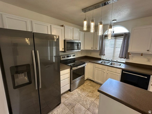 Kitchen featuring a stainless steel side-by-side refrigerator, white shaker-style cabinetry, and a stainless steel range with an over-the-range microwave