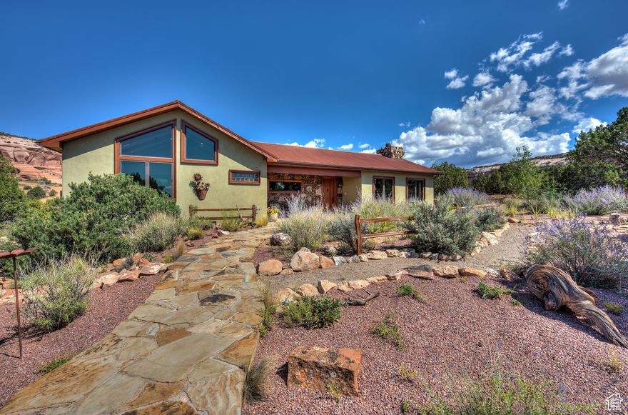 PERFECTION IS IN THE DETAILS - Simply stunning desert retreat perfectly situated on 2.63 acres an easy 30-minute drive from downtown Moab. Surrounded by red rock formations, snow-capped peaks, iconic parks and trails, and minutes from the renowned Wilson Arch, this home is perfectly positioned for adventure and tranquility. Hike from your patio, bike world-class trails, explore 4x4 routes, and so much more.  The fully furnished home perfectly balances privacy and accessibility, with natural xeriscaping, a stacked rock entry, and a welcoming front walkway. Inside, the great room stuns with vaulted timber ceilings, picture windows, and artisan details like custom cabinetry, rockwork, and a striking fireplace. White oak and slate tile floors flow through an open layout that connects living, dining, and a chef's kitchen with granite counters, high-end appliances, and a generous island for gathering. The main suite is a peaceful retreat with a second fireplace, dual designer closets, spa-style en suite, and private patio access with a hot tub for soaking under the stars. A bright guest bedroom, stylish hall bath, and integrated laundry add convenience and comfort. Outdoor spaces shine with a Viking outdoor kitchen, covered patios for dining and relaxing, and a serene outdoor shower. The detached garage includes a climate-controlled 500 square foot guest room, and the oversized two-car garage provides space for all your gear. An included second parcel preserves your views and enhances privacy elevated desert living, through and through.