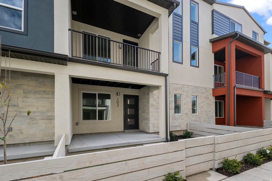 Enjoy unbeatable convenience with quick access to I-15, I-215, downtown Salt Lake City, and the airport-all just minutes away. Walk to nearby parks, schools, and the scenic Jordan River Trail, or take advantage of community amenities including a central park, BBQ area, and abundant guest parking.  Step inside to an open-concept floor plan that feels both stylish and welcoming. Soaring cabinets in a bold, moody finish anchor a spacious kitchen built for gathering, while large living and dining areas flow seamlessly to a generous private balcony-perfect for relaxing or entertaining.  Oversized windows throughout the home invite in abundant natural light, while a fenced-in front yard offers privacy and additional outdoor space. Built with sustainability in mind, this home features enhanced insulation, high-efficiency windows, instant hot water, solar-ready wiring, and a private garage with EV outlet-designed to deliver long-term comfort and savings.  Don't miss the opportunity to own a thoughtfully designed, energy-smart home in one of the most accessible and vibrant areas of the valley. This one is a must-see.