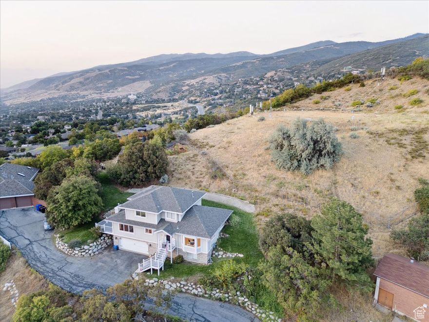 Beautifully maintained East Bench two-story with breathtaking lake, valley, and sunset views. Nestled on nearly half an acre just steps from Bountiful Ridge Golf Course and Mueller Park, this home offers both natural landscaping and a grassy yard for play and entertaining. The bright, modern kitchen has been tastefully updated and opens to a vaulted great room and expansive deck-perfect for gatherings with a view. The spacious main floor bedroom and primary suite feature a luxurious bath with oversized soaking tub, separate shower, dual sinks, and radiant heated floors. Hardwood floors on the main level, well-kept carpet throughout, and fresh, neutral paint provide a warm and move-in-ready feel. The lower level includes a large bedroom currently used as a family room, adding flexibility to the floor plan. A new roof was installed by the previous owners in 2023, along with new water lines throughout the home, giving peace of mind for years to come. Additional highlights include ample storage and quick access to Salt Lake City, the airport, and world-class recreation. Just 15 minutes to downtown and tucked into one of Bountiful's most desirable neighborhoods-this home blends comfort, convenience, and views you'll never tire of. $7500 credit offered through preferred lender.