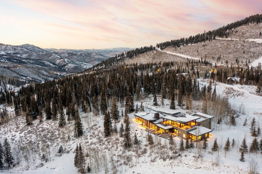 Perched in one of Park City's most coveted communities, this Colony home is set on one of the finest lots this esteemed enclave offers. The artesian modern architecture seamlessly blends into its natural surroundings while commanding attention with its refined elegance. Privacy, tranquility, and jaw-dropping views converge in a location that offers both seclusion and convenient access to world-class skiing, dining, and cultural experiences of Park City. Designed with an artisan's eye and an adventurer's heart, this residence showcases contemporary mountain architecture featuring soaring ceilings, walls of glass, and organic materials that honor the landscape-natural woods on the floor and ceiling, natural stone, steal, and custom millwork create warmth and authenticity, while clean lines and sophisticated finishes deliver unmistakable luxury. Expansive living areas flow effortlessly to outdoor terraces where fire pits warm your gaze under starlit skies and hot tubs steam against mountain backdrops, while the gourmet kitchen and butlers kitchen-a chef's dream with top-tier appliances and custom cabinetry-invites both intimate family dinners and grand entertaining, both indoor and out. Retreat to the primary suite, a private sanctuary with spa-inspired baths, walk-in closets, and views that make waking up feel like a privilege. Finish your day or enjoy a lazy afternoon on the rooftop deck spanning over 1,800 sq ft with views in every direction. This is mountain living elevated: ski-in/ski-out access means powder days begin at your doorstep, summer unveils endless trails for hiking and mountain biking right from your property, yet you're mere minutes from Park City's historic Main Street, fine dining, art galleries, and private clubs-offering the perfect balance of adventure and sophistication.