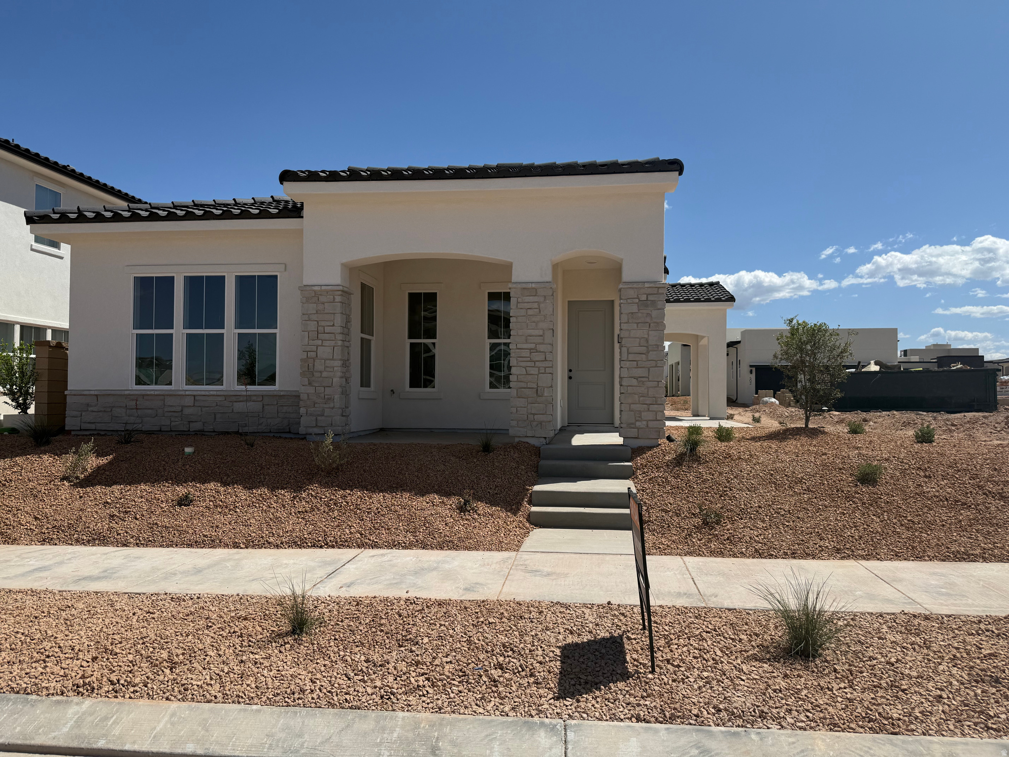 Contemporary stucco exterior with stone accents and a terracotta tile roof