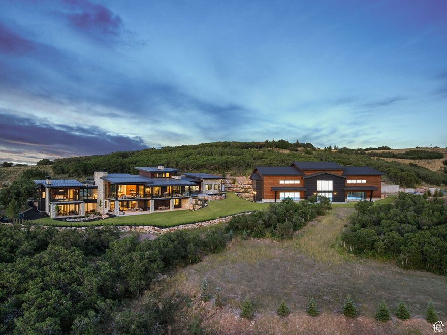 Perched on 24.68 acres in the gated Ranches at the Preserve-one of Park City's most private and expansive neighborhoods-this newly built estate, including a separate structure with indoor tennis court, is a rare combination of seclusion, sophistication, and proximity to everything Park City has to offer. Surrounded by untouched nature, yet only 10 minutes to Kimball Junction and just 25 minutes to Historic Main Street, this legacy property offers the best of both privacy and convenience. Crafted for luxurious main-level living, the 10,954-square-foot residence showcases striking architectural design and refined craftsmanship throughout, from custom cabinetry and woodwork to curated designer lighting and finishes. An expansive great room with vaulted ceilings and a wall of glass that opens at the push of a button invites the outdoors in, framing panoramic views of the Wasatch Mountains and ski resorts. Multiple outdoor living spaces provide unforgettable backdrops for entertaining or relaxation. At the heart of the home is a stunning chef's kitchen, designed with both form and function in mind. Two oversized islands provide ample space for cooking and gathering, while a fully equipped butler's pantry ensures seamless entertaining and storage. The primary suite is a private sanctuary with spa-caliber amenities, generous closet space, and private terrace access. For focus and productivity, enjoy a private executive office and a fully equipped conference room, also ideal as a second office, both enhanced by expansive mountain views and situated in a private wing inside the house. Additional features include a dedicated exercise room, multiple gathering spaces, and a custom bunk room with eight built-in beds, creating a luxurious yet practical retreat for guests or family. The showpiece of the property is the 8,907-square-foot indoor sports facility, designed to meet USTA specifications for tennis, with the versatility to accommodate a basketball court or four pickleball courts. Beyond sport, this one-of-a-kind space offers endless possibilities: transform it into a world-class car gallery, private event venue, music and film studio, or a health and wellness retreat with room for a full gym, lap pool, and golf simulator. For outdoor enthusiasts, take advantage of direct access to the Glenwild trail system from your backyard for miles of hiking, biking, and year-round outdoor adventure. For equestrian lovers, there is a large fully irrigated pasture, and the foundation for a stable has already been poured and plans approved by the HOA and county. Wildlife roam freely around the estate, enhancing its sense of escape, while everyday conveniences remain close at hand. Skiers will appreciate being within 20 minutes of Park City Mountain, Deer Valley, and only 10 minutes from Woodward resorts. 5 minutes from the private Glenwild Golf Club-Park City's premier country club offering world-class golf, dining, and amenities-and only 30 minutes from Salt Lake City International Airport and the vibrant downtown Salt Lake City.