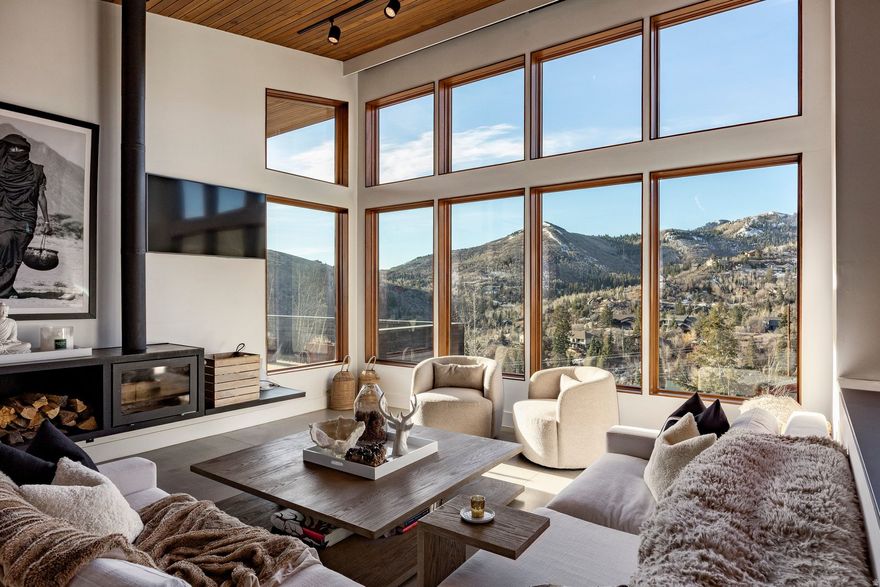 Perched along a scenic mountain ridgeline in Park City, this striking modern home captures breathtaking 180 south-facing views and backs directly to open space with private access to the Pinebrook trail network. Built with both beauty and efficiency in mind, the home showcases sleek modern architecture wrapped in preserved Shou Sugi Ban wood and weathered steel, along with radiant floor heat, passive solar design, earth cooling, high-efficiency insulation, and on-demand hot water. The open-concept design features vaulted ceilings and expansive floor-to-ceiling windows that fill the home with natural light and showcase the surrounding mountains. A spacious, 30X30 deck off the dining area creates seamless indoor-outdoor living, perfect for year-round entertaining. The main-level primary suite offers a peaceful retreat with private deck space, while the lower level includes three additional bedrooms including multiple gathering spaces for family and guests. An oversized two-car garage provides ample storage for outdoor gear. Located minutes from world-class skiing and just 25 minutes to SLC Intl Airport, w/neighborhood parks, pickleball, tennis, and basketball courts.