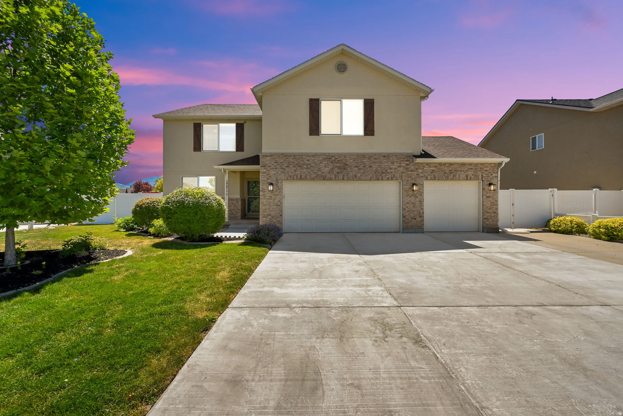 Two-story residence featuring a neutral stucco and brick facade with a 3-car garage