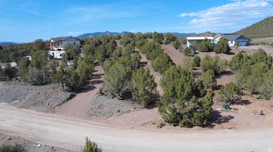 1.11-ac lot in Old Iron Town just minutes from Cedar City. Backs directly to National Forest with no rear neighbors--only wildlife, open space, and incredible privacy. The upward sloping terrain creates the perfect opportunity for an elevated build, maximizing breathtaking east-facing views of the Pine Valley Mountains and beautiful forest views to the west. Ideal for a custom home, cabin, or second retreat. Power and water are located at the front property line; water connection fee is $7,500. Improvements include a partial round driveway with compacted road base, septic hole excavation started, and perimeter groundwork completed. Soils report is completed and available. Enjoy peaceful rural living, dark night skies, abundant recreation, and convenient access to Cedar City for amenities.