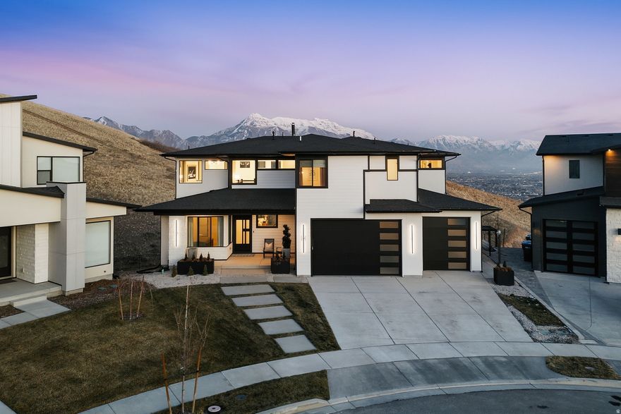 Wake up to unobstructed, panoramic views of Mount Timpanogos, Utah Lake, and the Valley from this modern architectural designed home with newly finished turf landscaping. Situated on a rare half-acre cul-de-sac lot backing natural open space, the home offers immediate access to mountain trails for hiking and biking. Designed for longevity and serenity, the floor plan blends effortless everyday living with elevated entertaining with a pivot-style modern front door. The heart of the home is a true chef's kitchen with premium JennAir appliances, double dishwashers, custom cabinetry, a waterfall quartz countertop island, stacked uppers with glass, walk-in pantry, and room for a butler's pantry. A 15-foot multi-slide glass door opens the great room to an expansive deck with views that never quit. The spa-like owner's retreat features a fireplace, stand-alone tub, massive walk-in shower, automatic shades and large custom closet. Finished, daylight walkout basement that opens to an additional patio, deck with a swim-spa with uninterrupted views. 6 bedrooms, 6 full baths plus 2 half baths, 2 laundry rooms, and a coveted corner office with floor-to-ceiling windows. Four-car garage with 10-foot doors and room for a full-size boat or toys. Enjoy Traverse Mountain's clubhouse, resort like pool and exercise amenities unmatched with any other community.