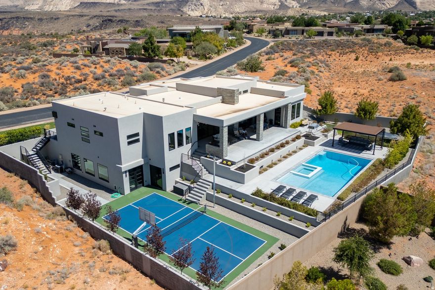 Entering through the striking metal-glass front door into a bright, open floor plan filled with tall glass sliding doors and modern fixtures that take in plenty of natural light and the surrounding sweeping mountain vistas. The kitchen is a showstopper with floor-to-ceiling cabinets, double waterfall quartz island, premium finishes, and 14' ceilings . A flexible gym or 4th bedroom comes with its own bath, while the spacious primary suite boasts large windows, a soaking tub, shower room with double shower heads, quartz double sinks, and a massive walk-in closet. Stackable sliding doors in both the living room and kitchen create seamless indoor-outdoor flow to the backyard retreat-complete with a sparkling pool and Shamu shelf, gazebo, pickleball court, fire pit, and in-ground trampoline. Three individual garage bays provide plenty of parking and storage. This is a modern entertainer's dream with all the right touches for year-round enjoyment. On the bench above Snow Canyon State Park and less than 15 minutes north of the city of Saint George. This property is also a short drive to some of America's most breathtaking destinations, including Zion National Park, Bryce National Park, and the north rim of the Grand Canyon. Other nearby state parks and national forests, include Sand Hollow Reservoir, Gunlock Reservoir, Quail Creek Reservoir, and Dixie National Forest that enhance the allure of the location. With over 300 days of sun, incredible year-round weather, and in the middle of a 7,200 yard par 72 golf course designed by Matt Dye, there is no doubt that The Ledges is one of Southern Utah's best kept secrets. One of the best places to live for those that love the outdoors, biking, hiking, fishing, ATVing, and all other high-desert adventures. All information herein is deemed reliable but is not guaranteed. The buyer is responsible to verify all listing information, including square feet/acreage, to the buyer's own satisfaction.