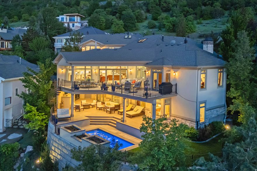 Experience the ultimate million-dollar panoramic views of the Salt Lake Valley and dramatic cliffs and colors of Little Cottonwood Canyon. Beautifully reimagined architecture brings exceptional quality craftsmanship, refined details and stunning features (the primary suite closet is to die for). Enter through the vaulted marble foyer into a grand great room anchored by a chef's dream kitchen-featuring top of the line appliances and dual oversized islands and expansive pantry, open dining room and exquisite temp-controlled and illuminated wine room, custom wood surround office and a main floor primary suite- all masterfully designed to keep the breathtaking views the centerpiece. An elegant, curved staircase ascends to a spectacular upper-level second primary retreat, complete with a spa-inspired bath featuring a custom round tub and a walk-in closet to rival all. The lower level is bright and spacious, offering a secondary great room, full kitchen, exercise studio, theater, laundry, three bedrooms, and two bathrooms-all with direct walkout access to a covered patio and a private saltwater pool with outdoor shower. Lutron Programmable Lighting (Connects through phone). Two private decks extend the living space outdoors, a four-car garage, and a heated driveway elevate everyday convenience. Framed by a tranquil waterfall and serene stream. One of Salt Lake's most exclusive estates, this home combines privacy and prestige with unmatched proximity to world-class ski resorts, premier medical centers, fine dining, shopping, and entertainment. *Square Footage is provided as a courtesy only. Buyer is advised to obtain an independent measurement and verify all information.*